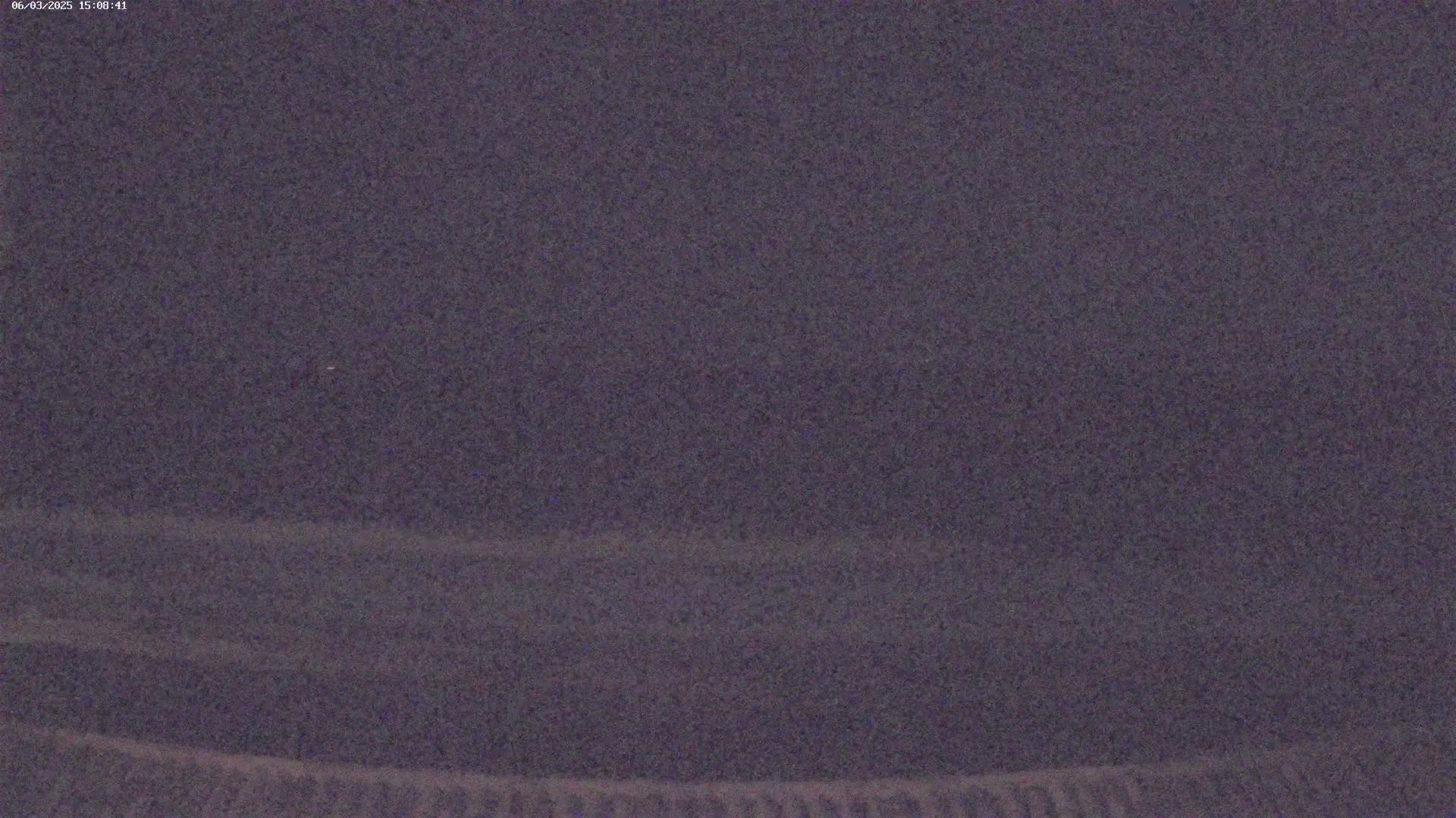 A dark, possibly nighttime, outdoor scene shows a mostly featureless, grainy sky and ground.