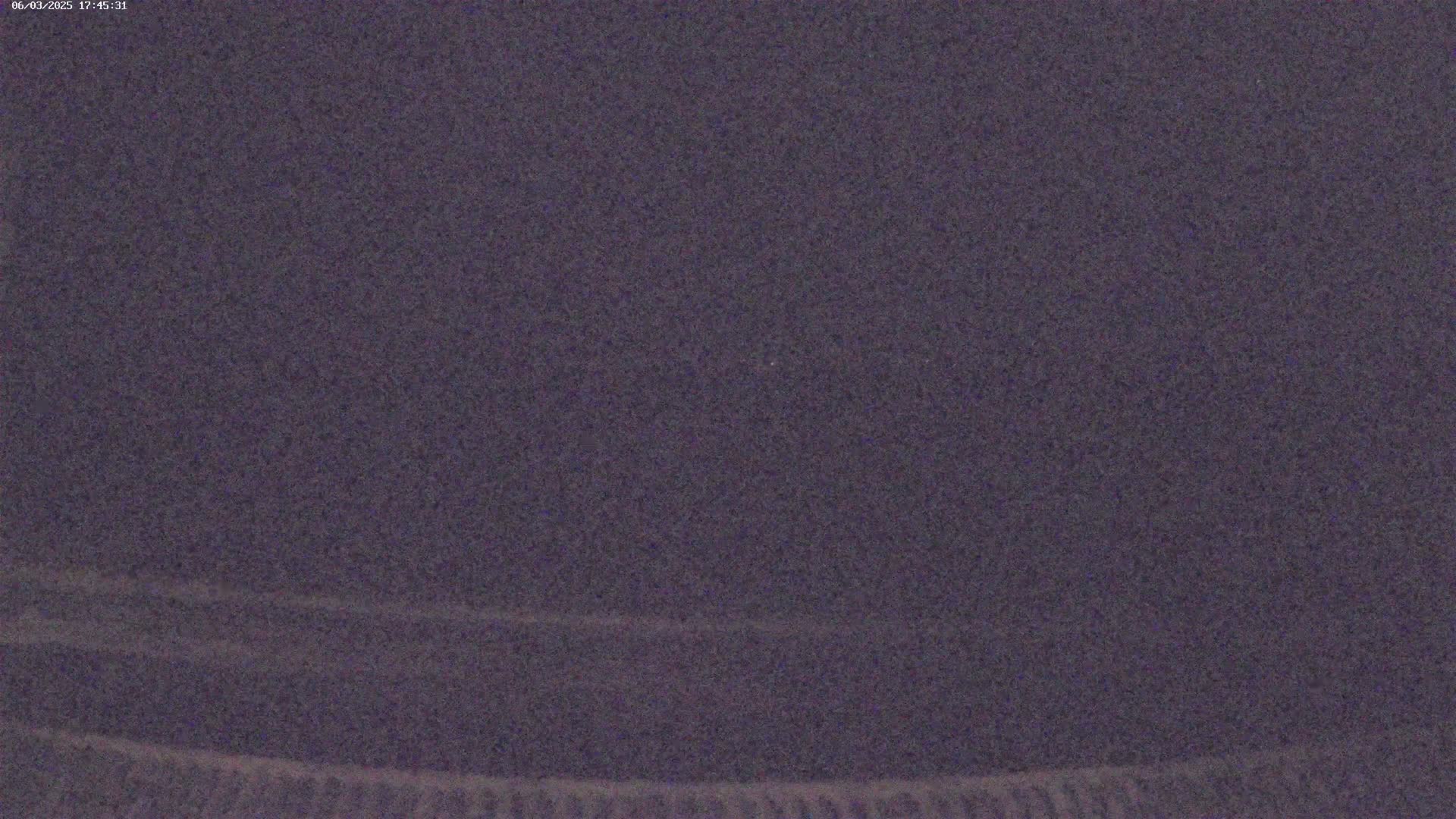 A dark, grainy image shows a mostly uniform dark purple-gray expanse with slightly lighter horizontal lines near the bottom.