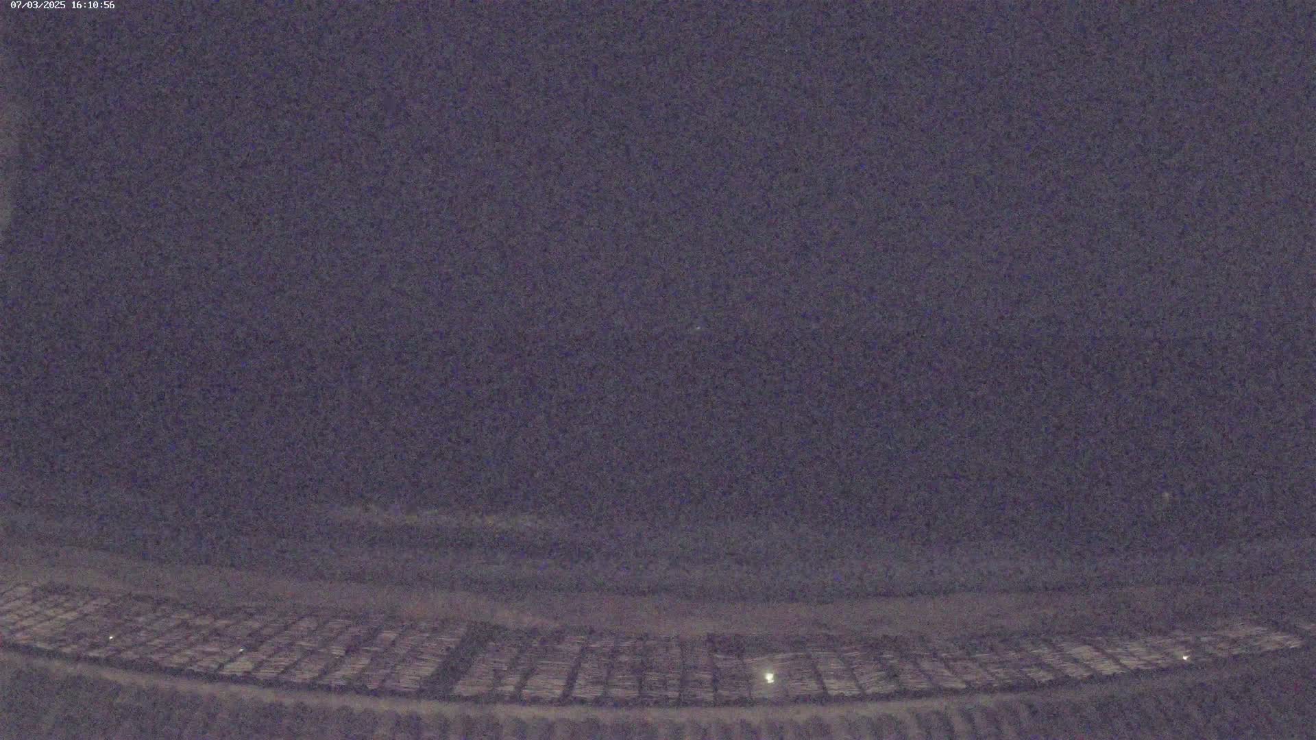 A nighttime view of a large, flat area with a grid-like pattern under a dark, possibly cloudy sky.