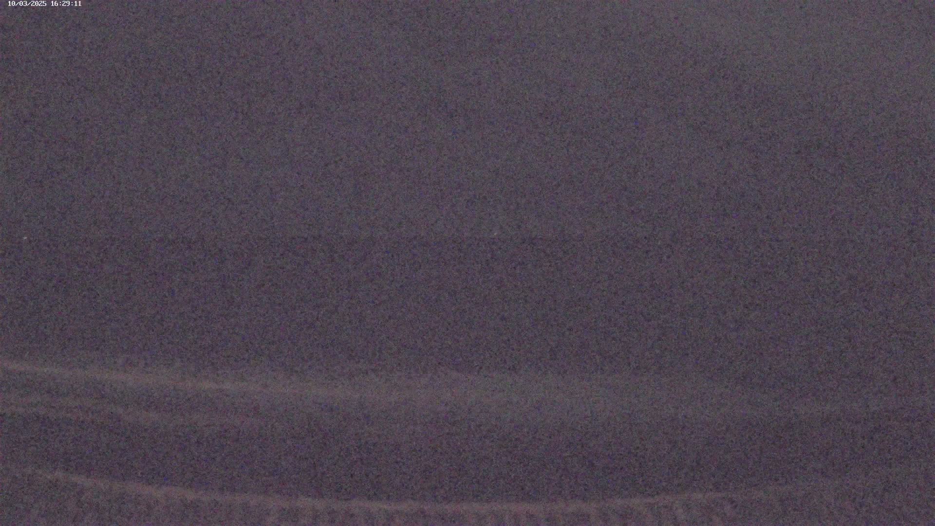 A blurry, dark gray image shows a mostly featureless landscape under overcast skies.
