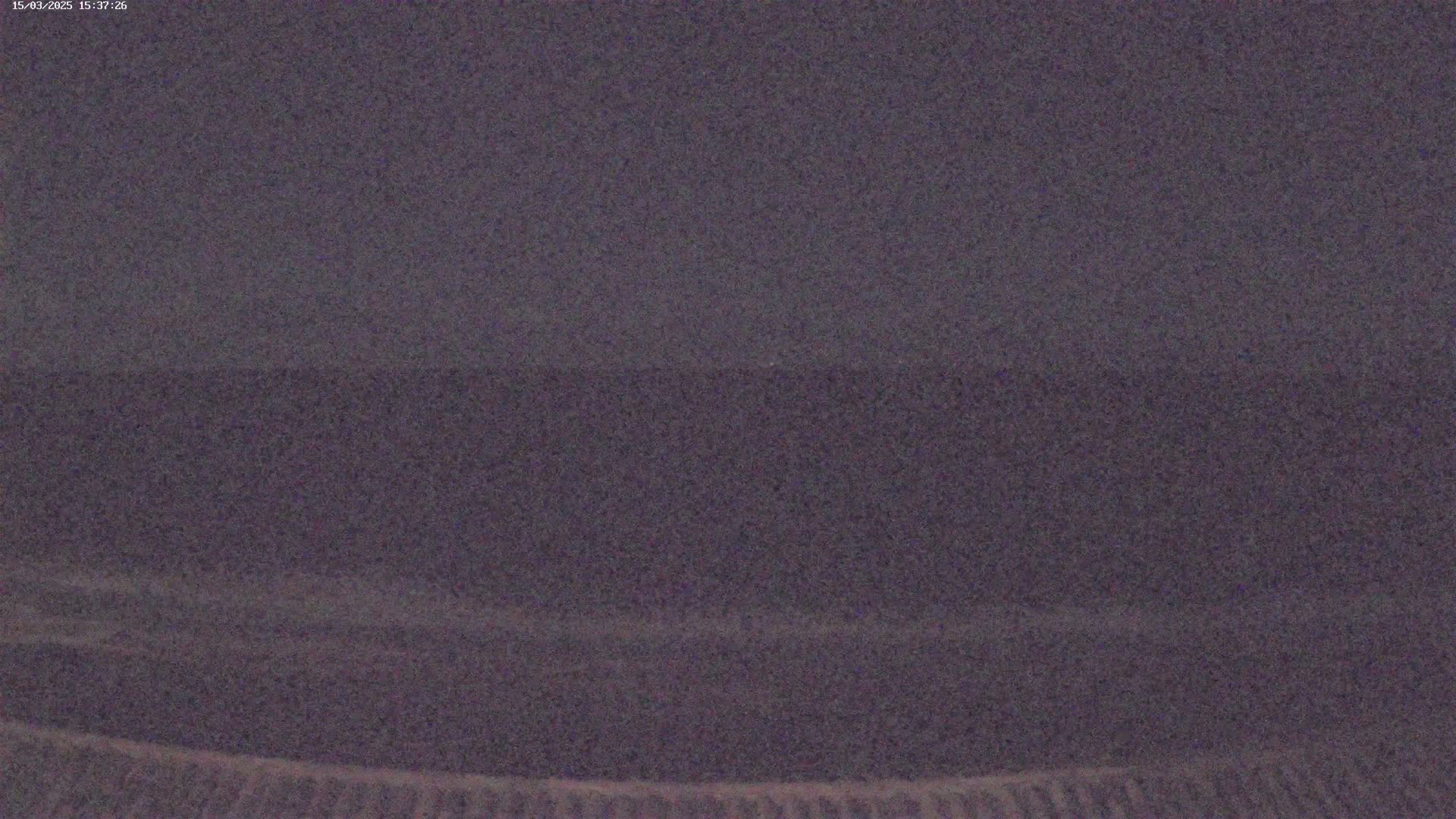 A blurry, dark gray image shows what appears to be a flat, sandy landscape under a dark sky.