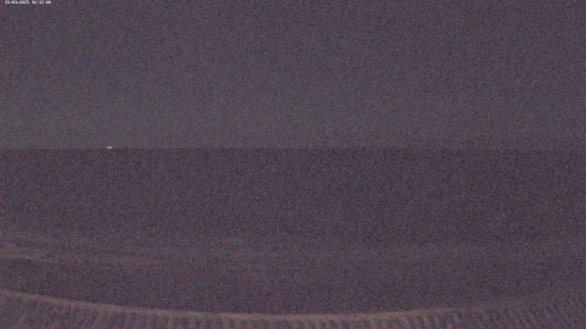 A dark, blurry image shows a dark body of water under a night sky.