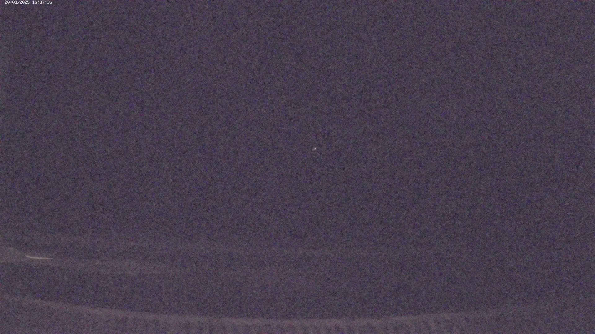 A single, faint light is visible in a dark, night sky.