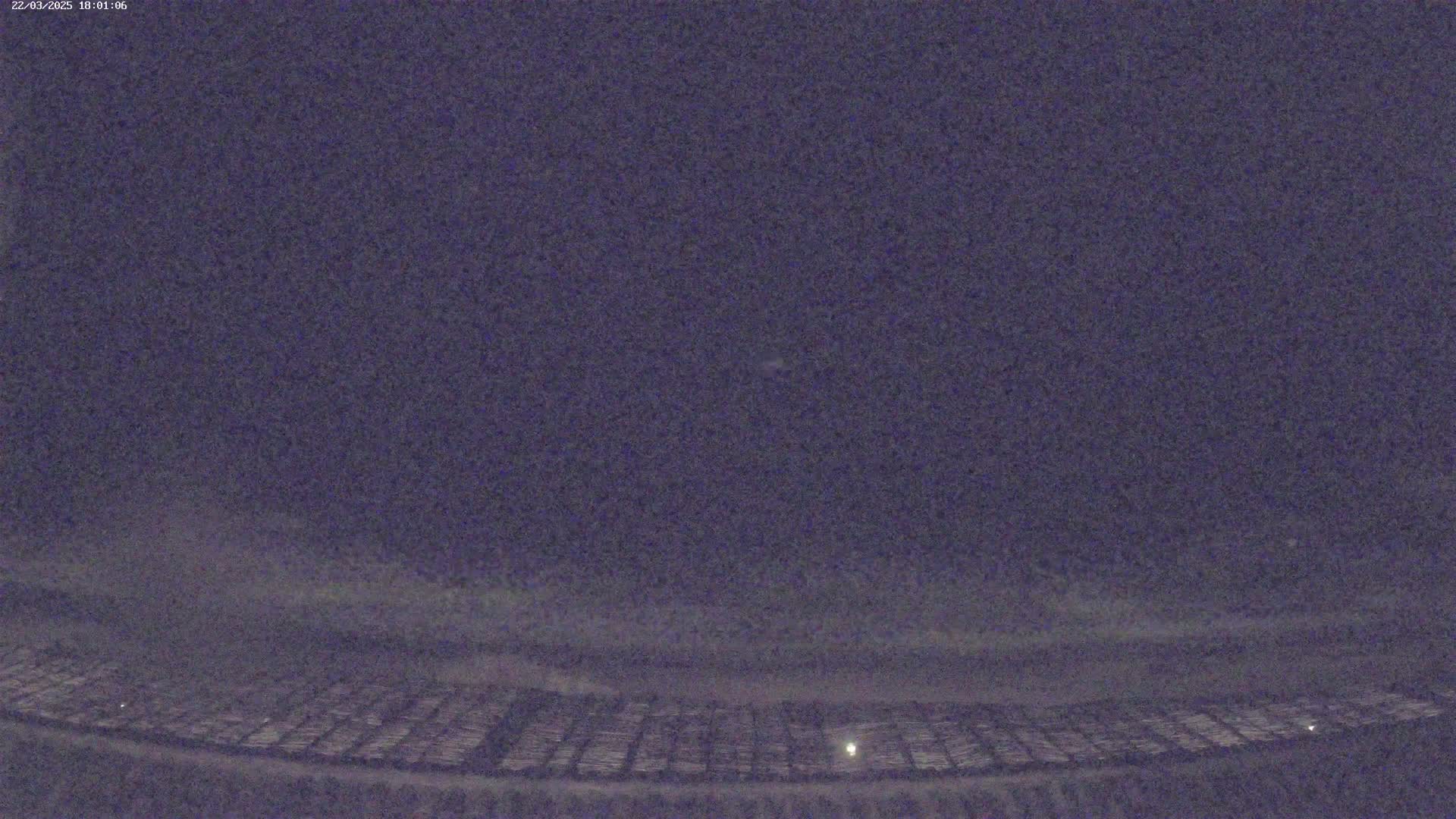 A nighttime, low-light view of a snow-covered field under a dark sky.