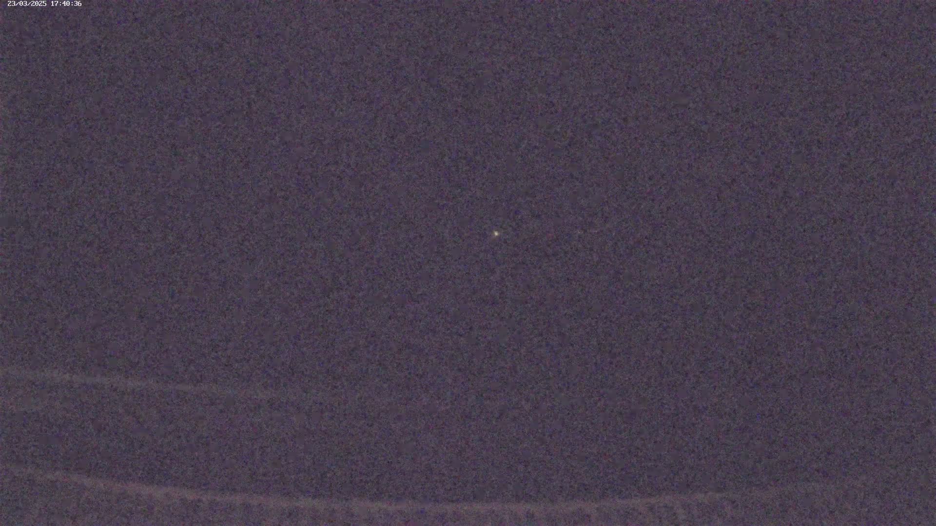 A single, faint light is visible in a dark, night sky.