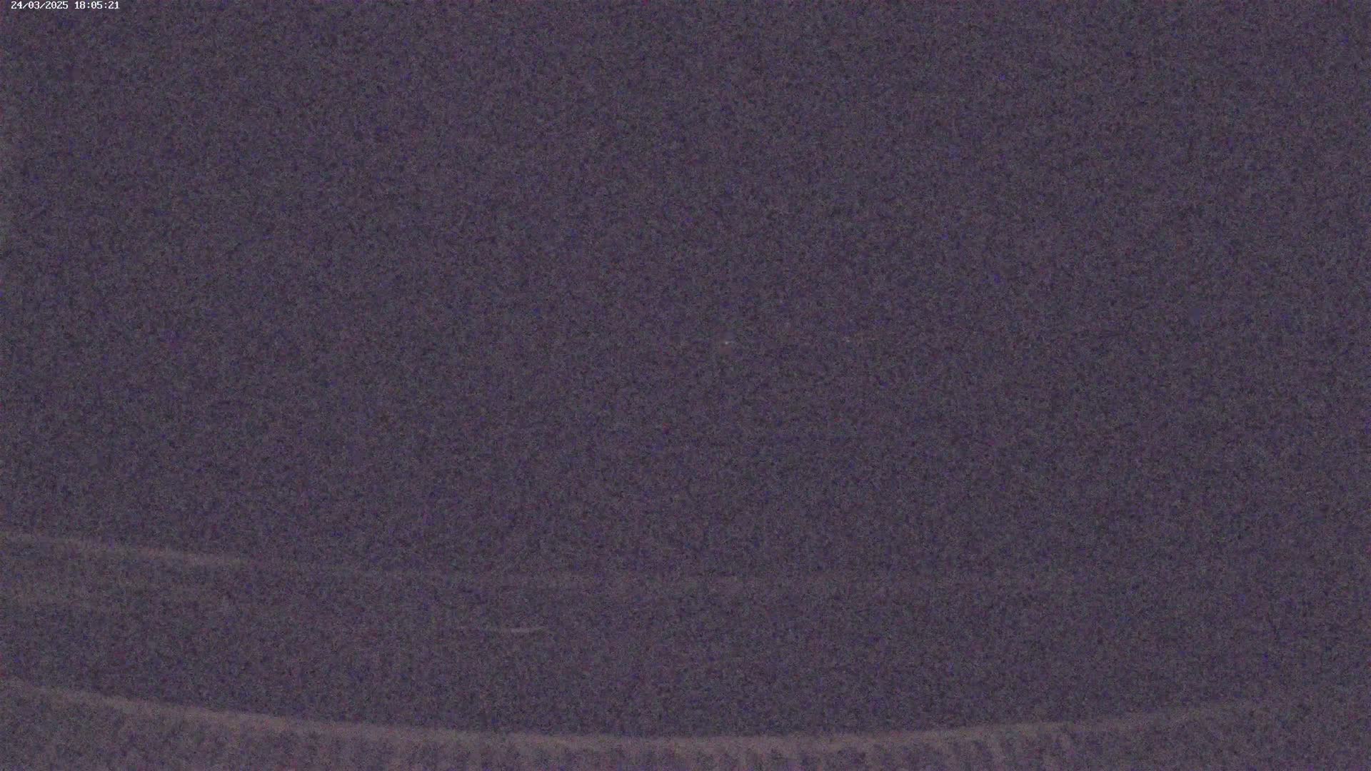 A dark, blurry image shows a mostly featureless, dark purplish-grey landscape at night.