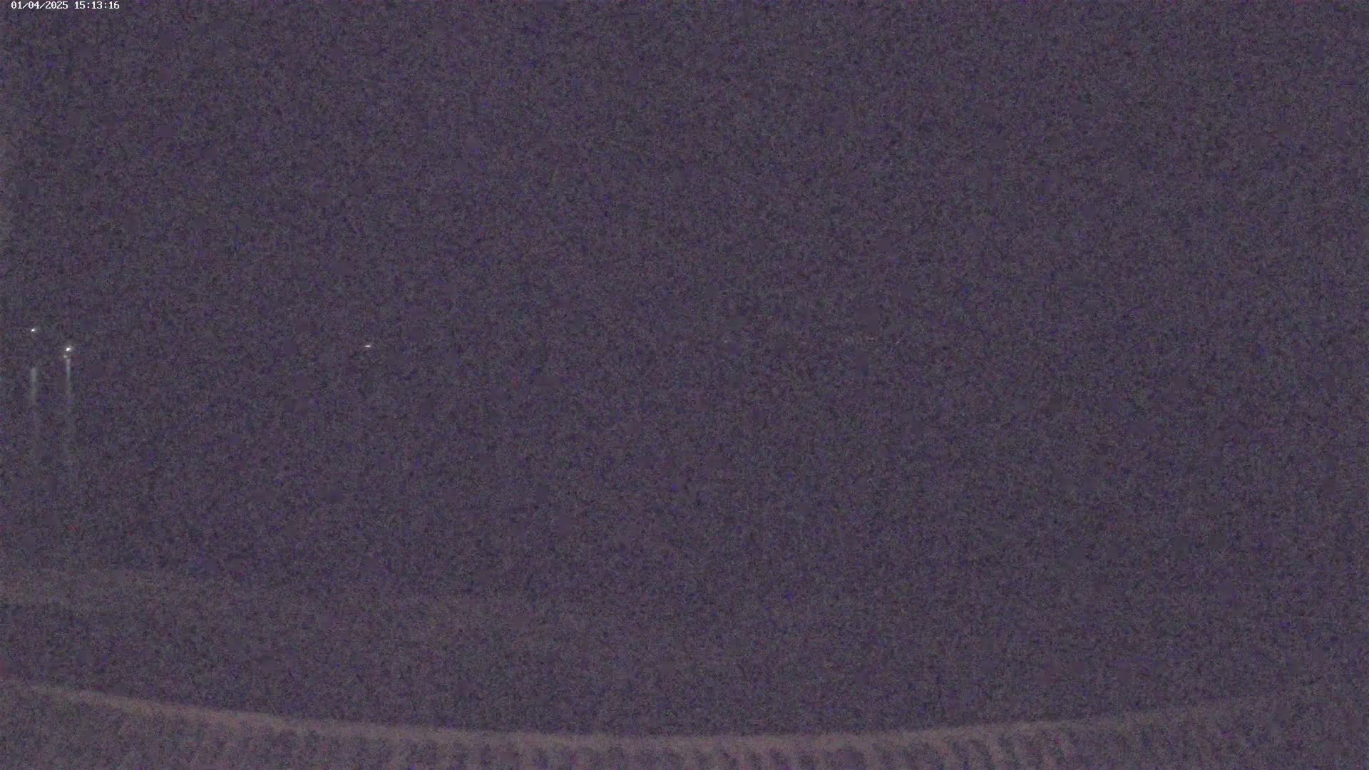 A nighttime, low-light view shows a dark, possibly overcast sky with a few distant lights visible.