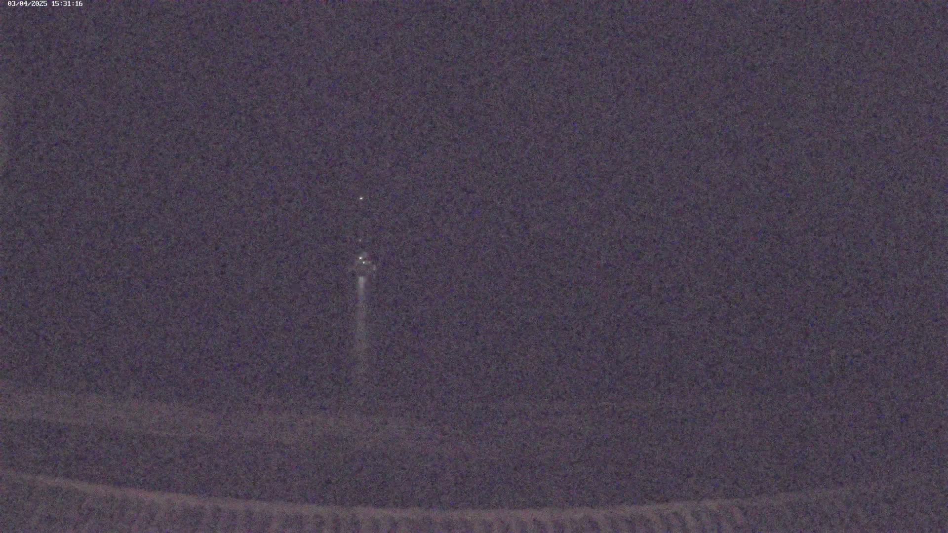 A faint light trail streaks across a dark, nighttime sky.