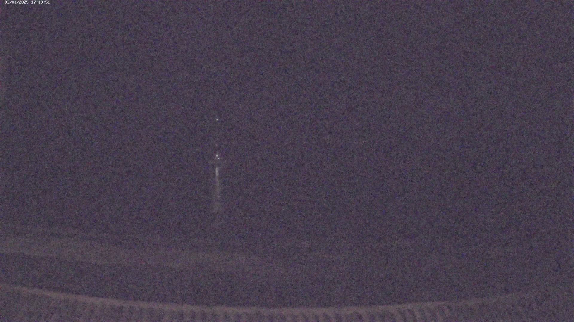 A faint, vertical streak of light is visible in the dark night sky.
