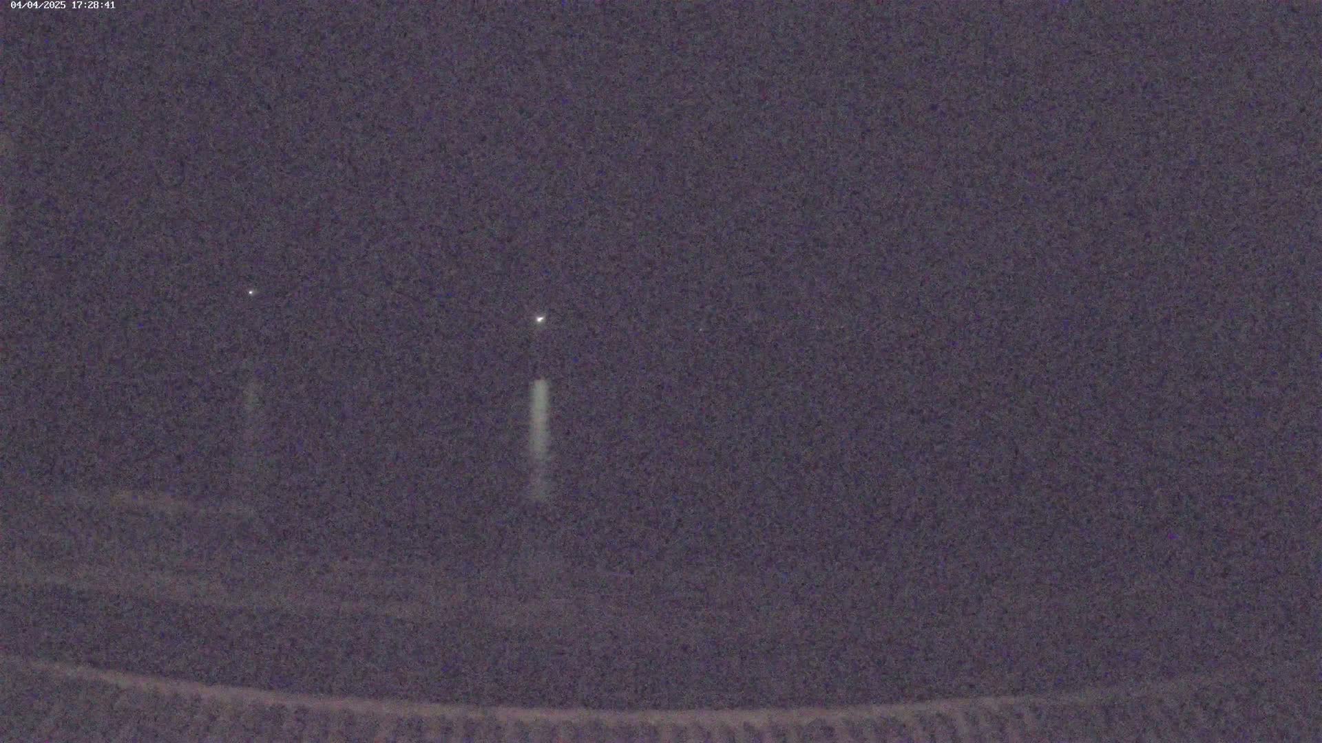 A nighttime, blurry image shows three faint lights in the dark sky, with one light appearing to have a vertical streak below it.