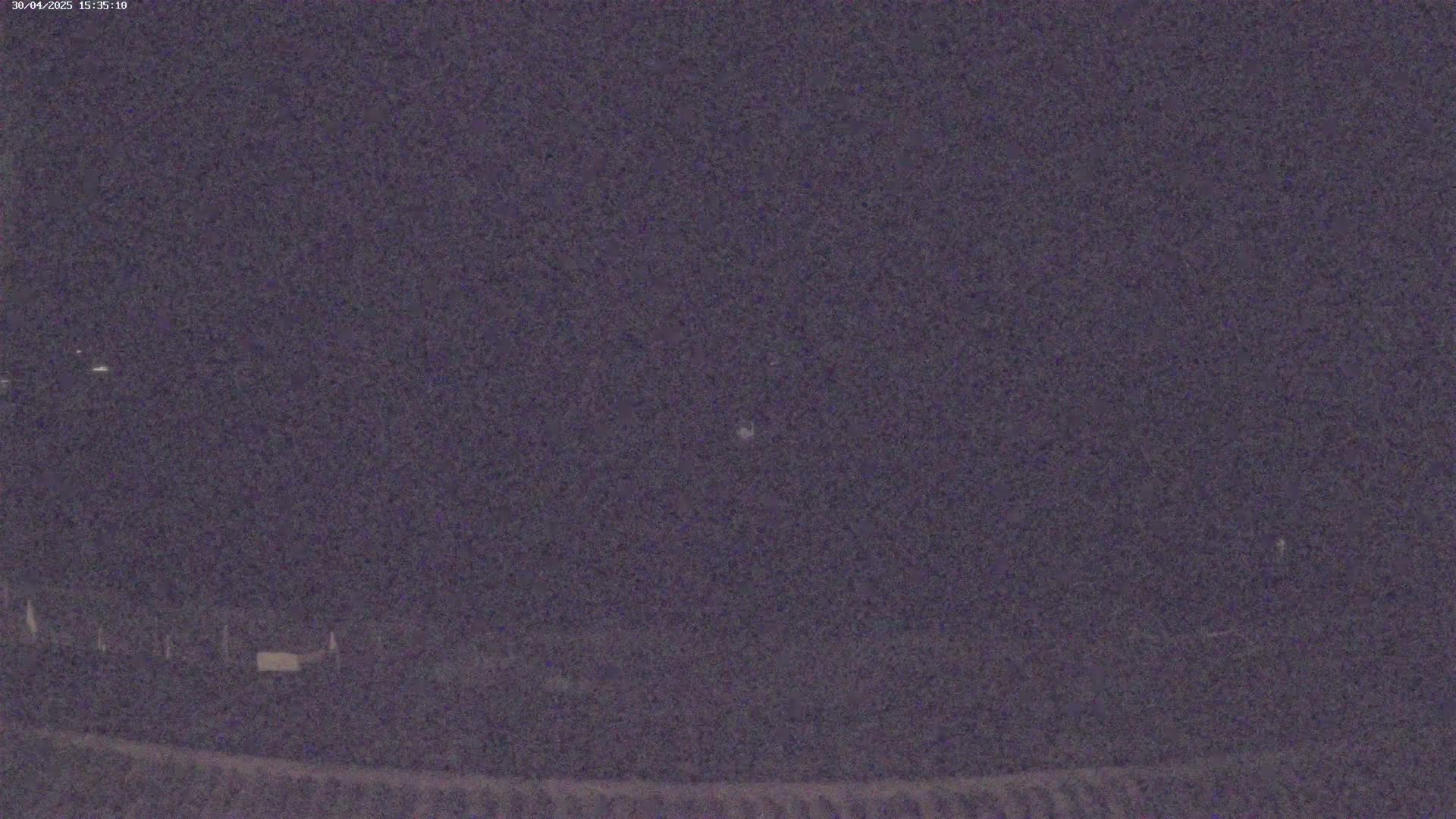 A dark, nighttime scene shows a blurry, indistinct landscape under a mostly clear sky.