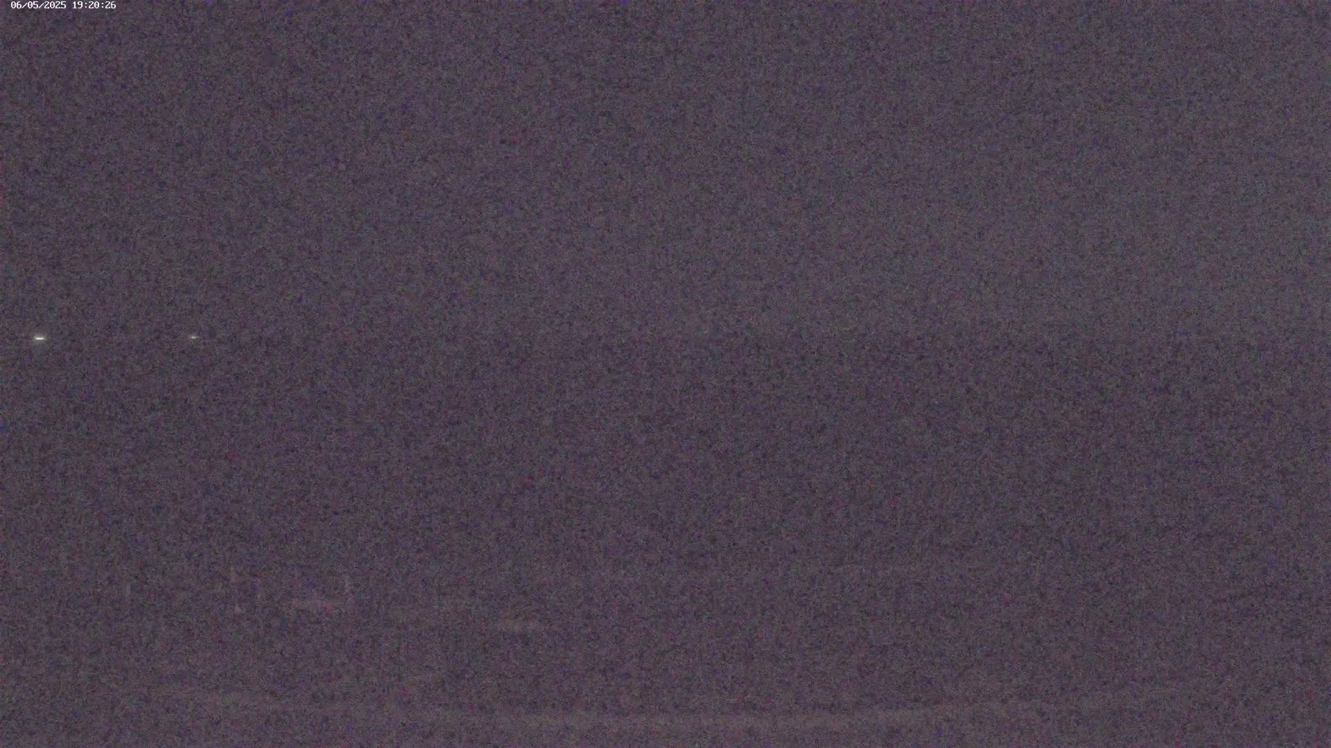 A dark, grainy image shows a mostly featureless night scene under a dark sky.