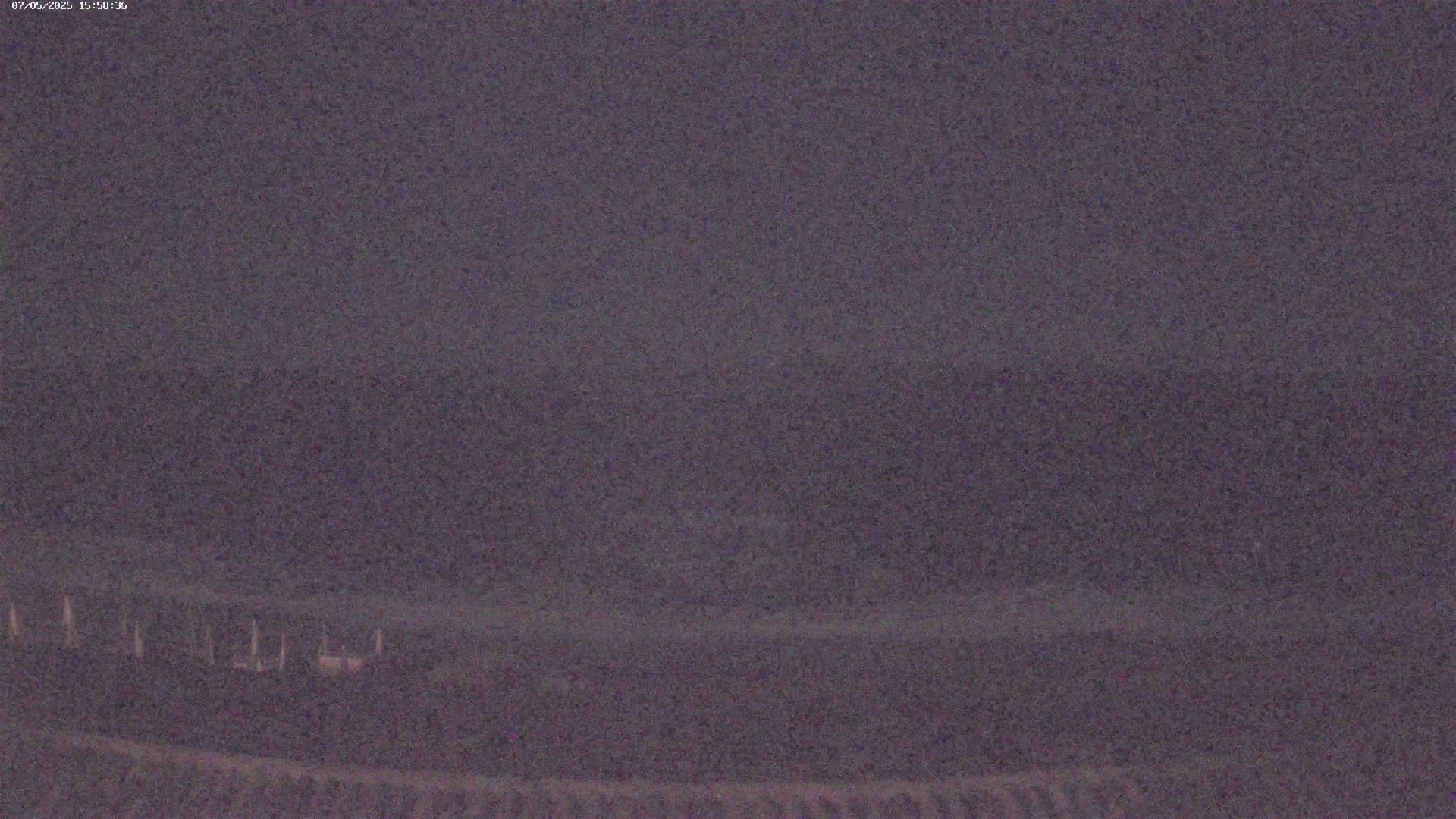 A low-light outdoor image shows a dark, possibly nighttime, scene with a few indistinct objects near the bottom.