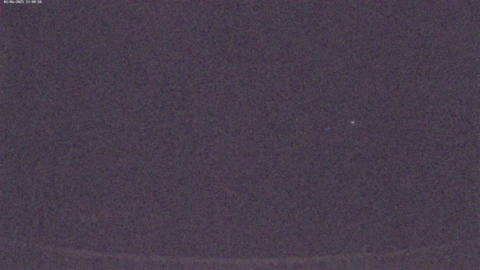 A single, faint light is visible in a dark, nighttime sky.