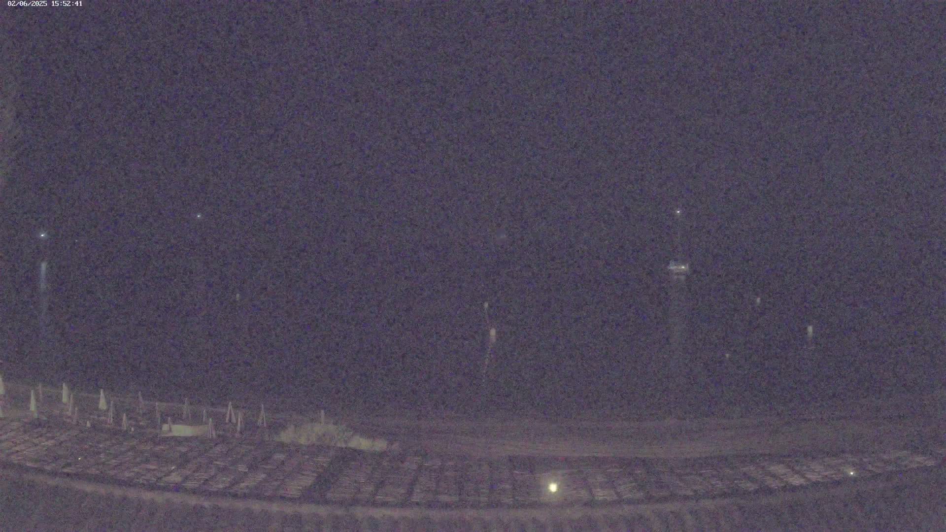 A nighttime view shows a dark expanse of land with faint lights and a few distant, bright lights in the sky.