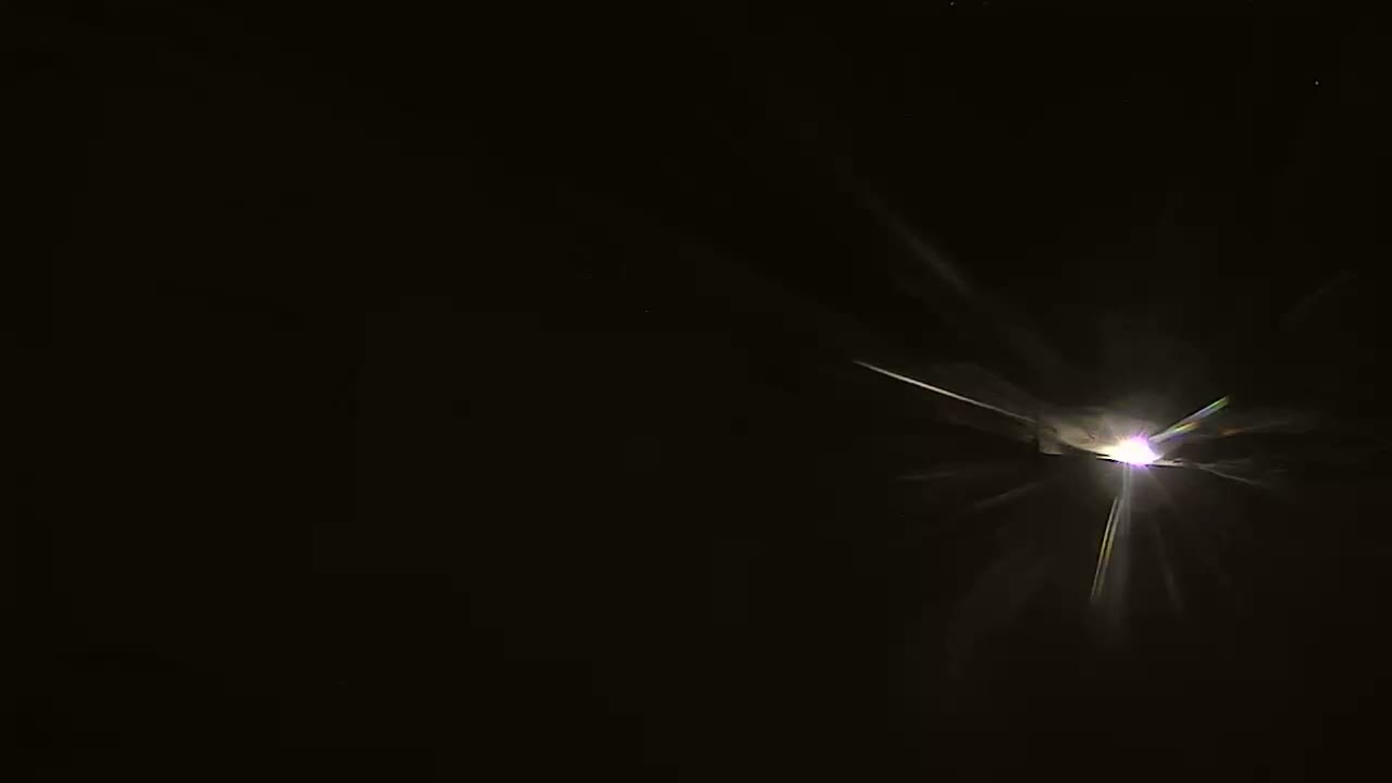 A bright light with radiating streaks emanates from the center of a dark, nighttime scene.