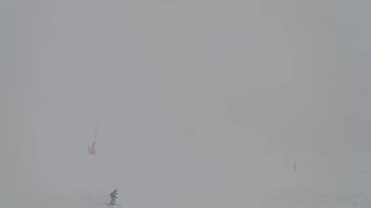 Two figures, one seemingly falling, are visible in a snowy, foggy landscape.