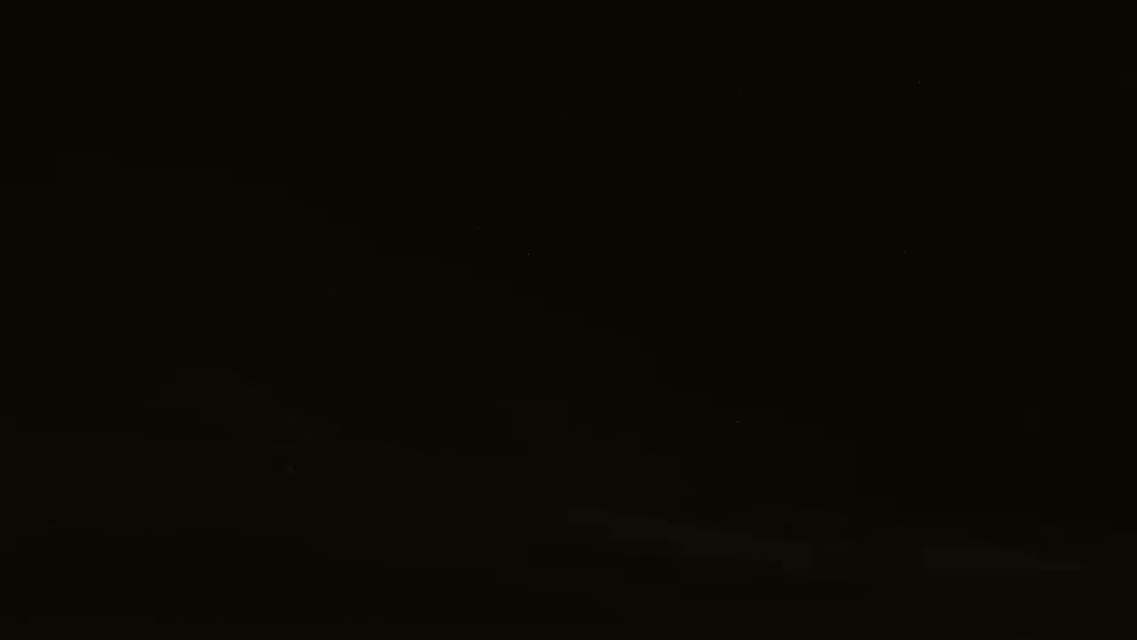 A very dark image shows a faint, blurry, light gray horizontal line near the bottom, suggesting a dark night scene with minimal light sources.