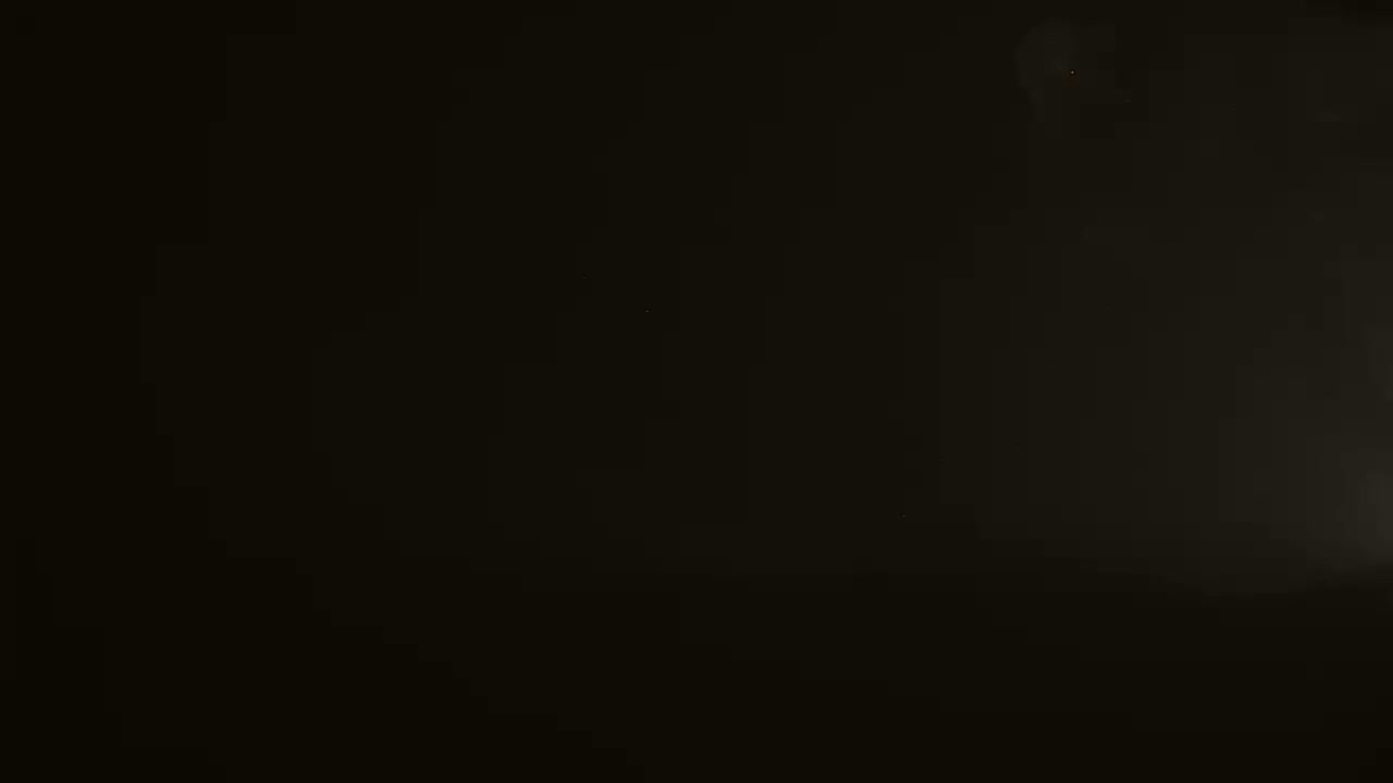 The image shows a mostly black background with a faint, hazy light source in the upper right corner.