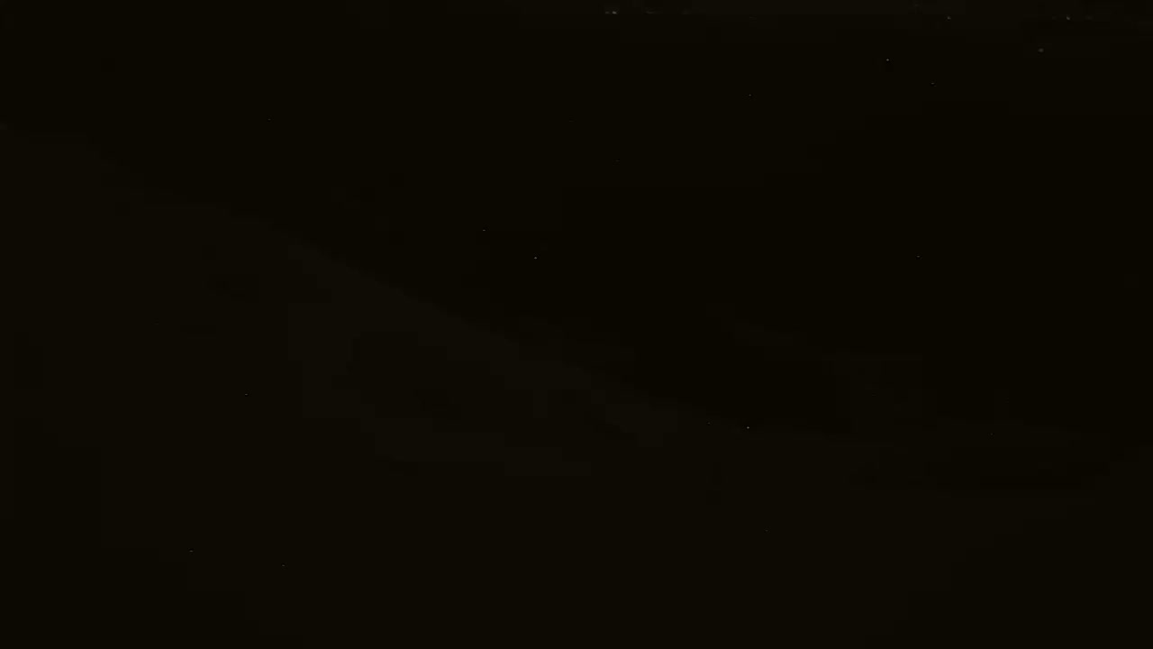 A mostly black image shows faint, blurry shapes and a few scattered specks of light.
