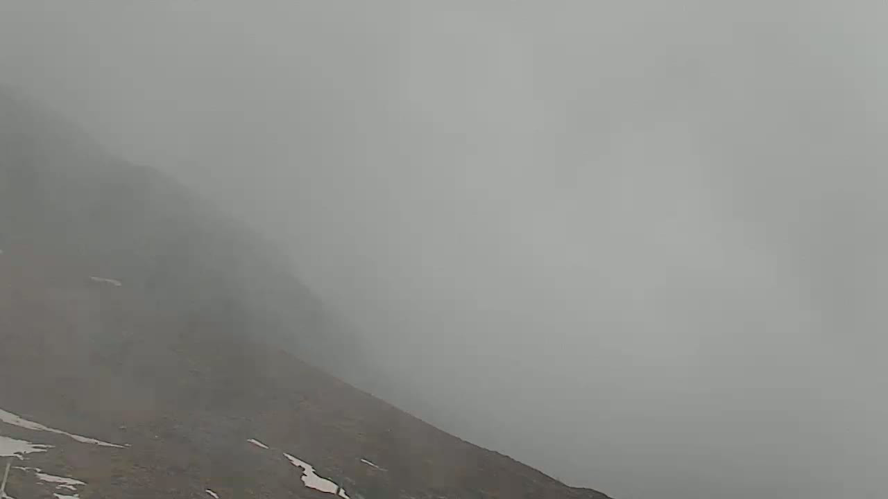 A foggy, mountainous landscape with patches of snow is visible.