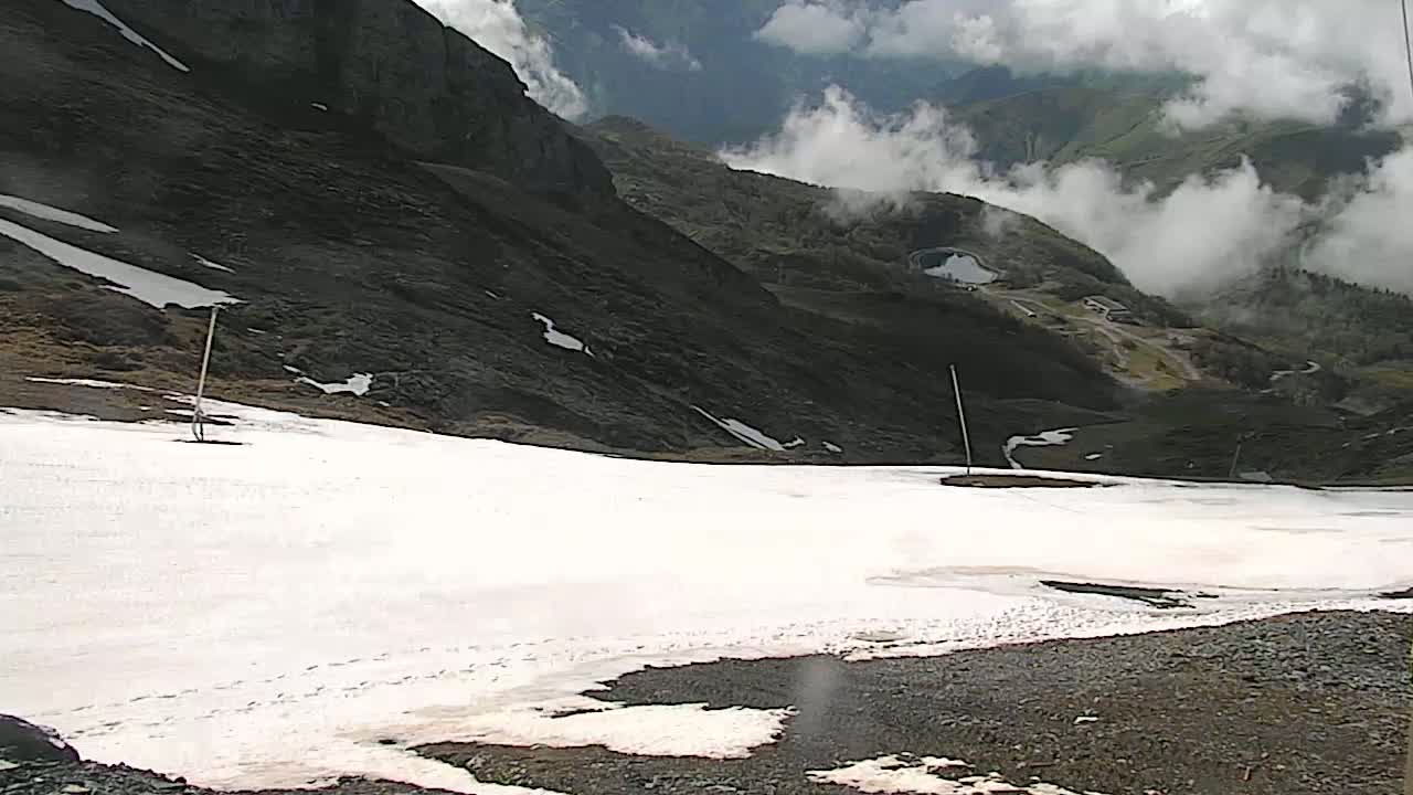 A snowy, mountainous landscape is partially obscured by clouds.