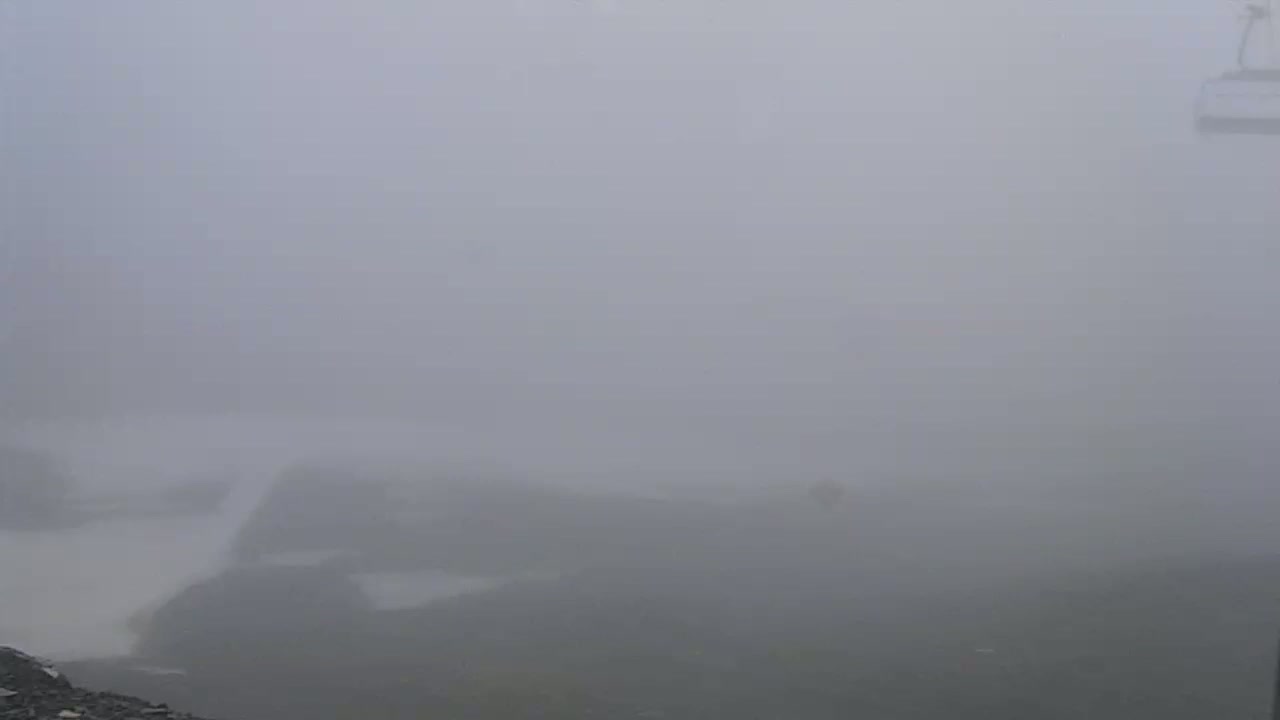 A thick fog obscures a mountainous landscape with a cable car partially visible in the upper right corner.