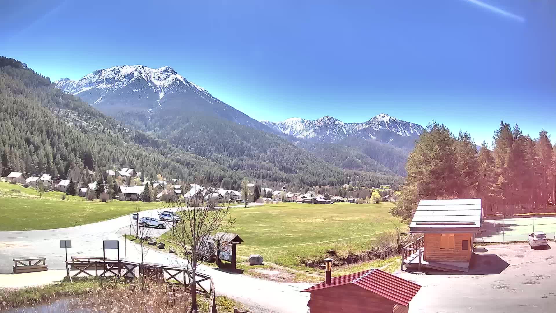 A small village nestled in a valley between snow-capped mountains on a sunny day.