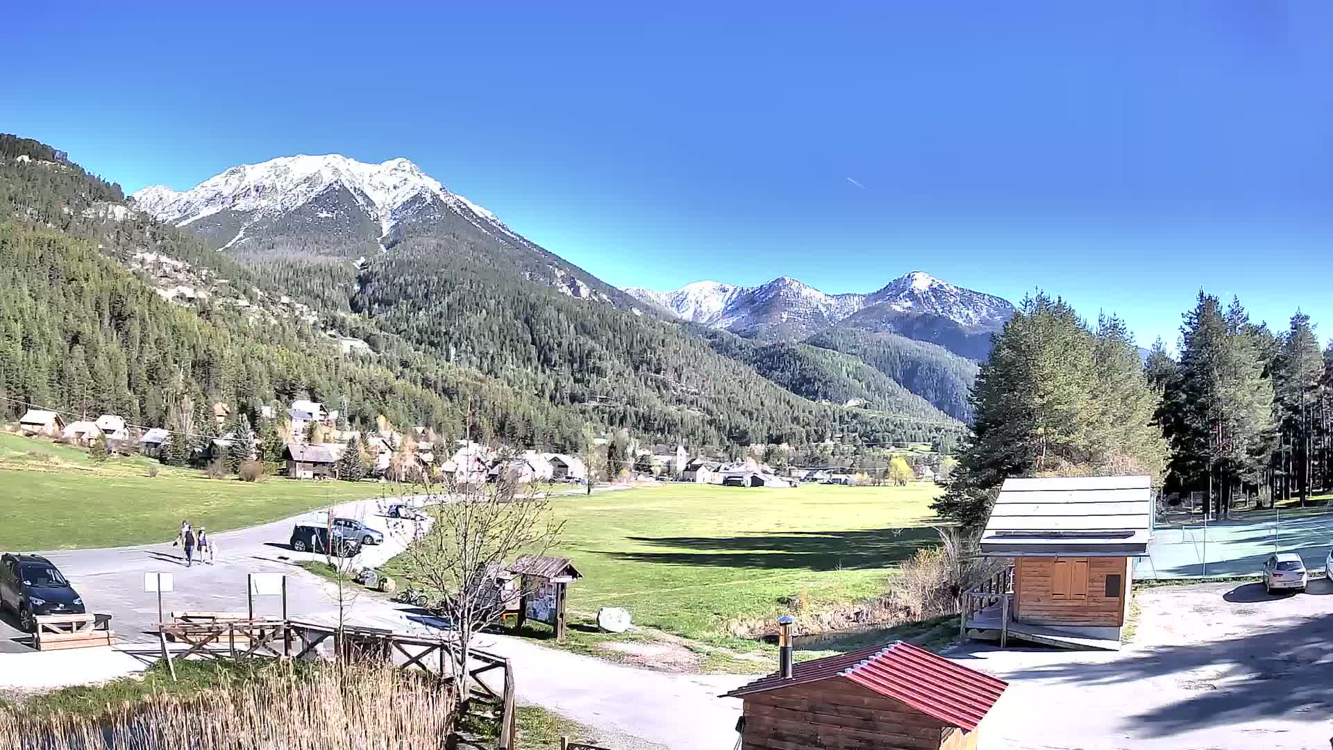 A small village nestled in a valley between snow-capped mountains on a sunny day.