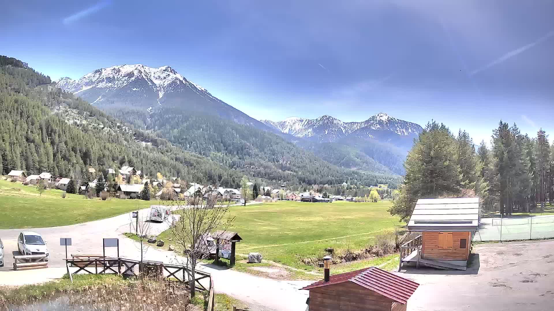 A small village nestled in a valley between snow-capped mountains on a sunny day.