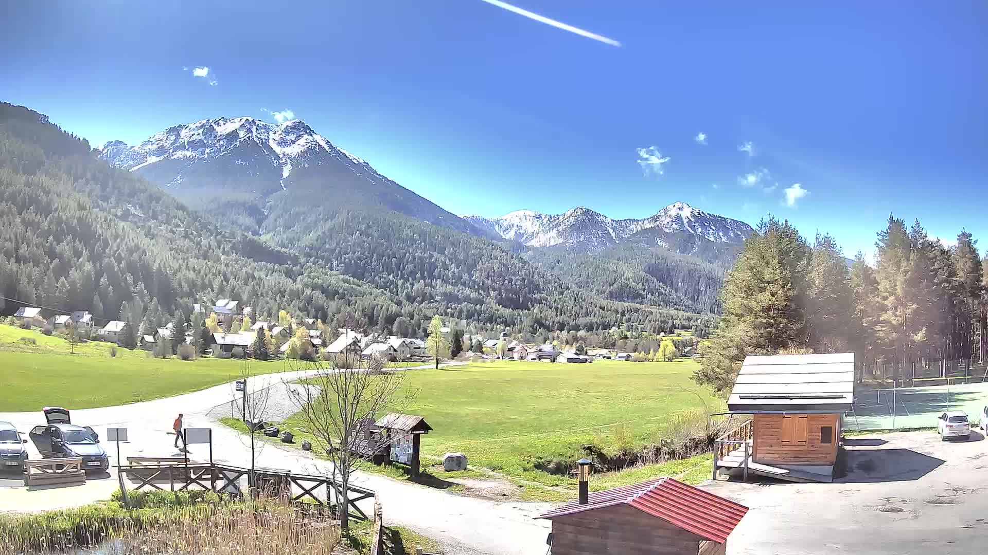 A small village nestled in a valley between snow-capped mountains on a sunny day.