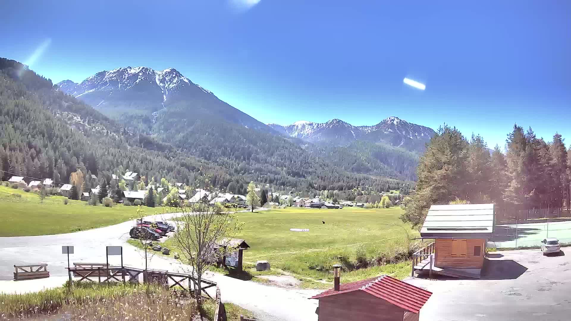 A small village nestled in a valley between snow-capped mountains on a sunny day.