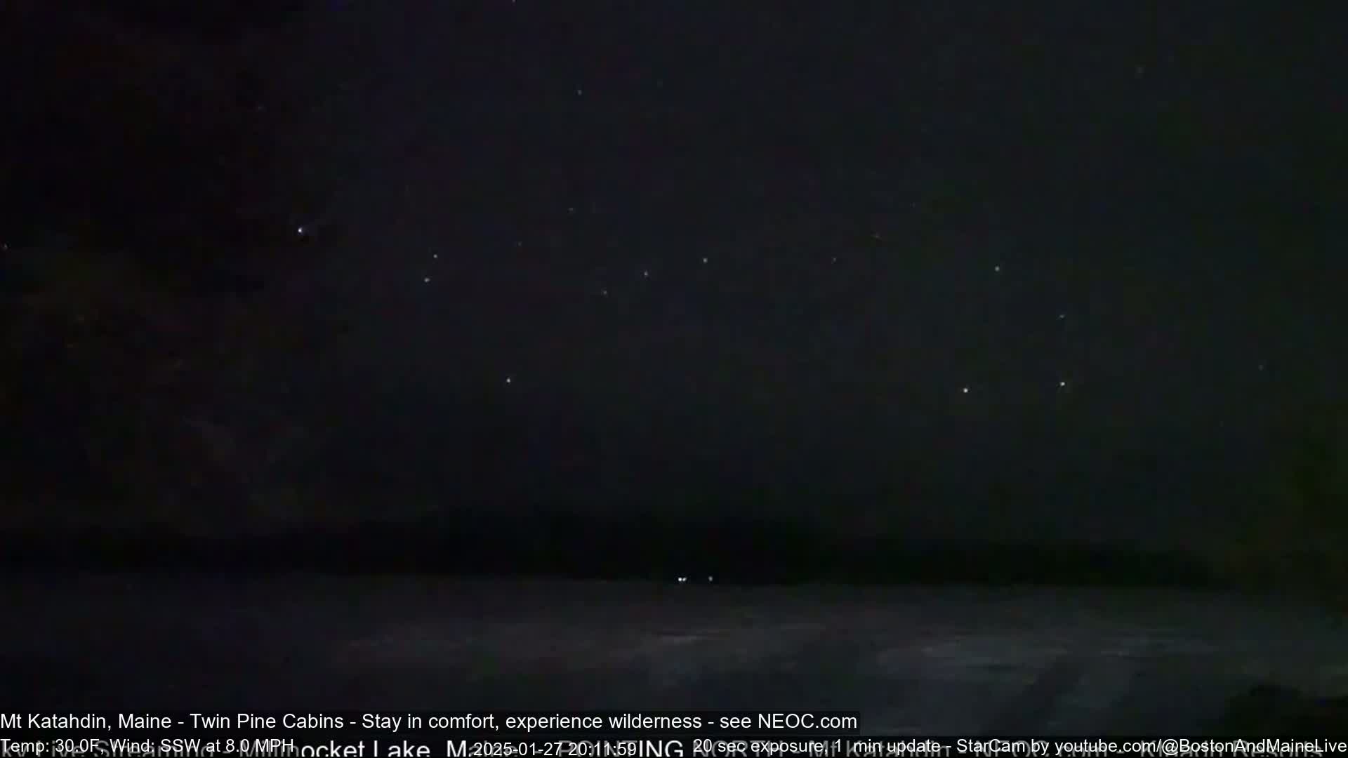 A nighttime long exposure shows a dark sky with stars and a dark, flat landscape.