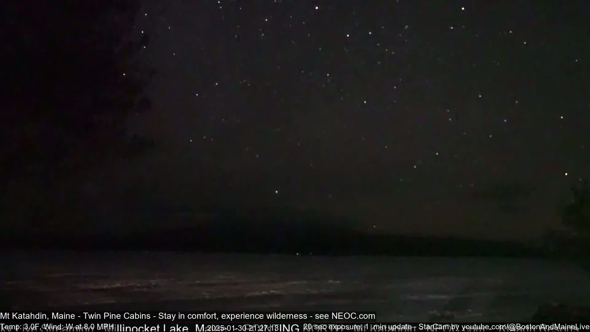 A dark, star-filled night sky overlooks a calm body of water.