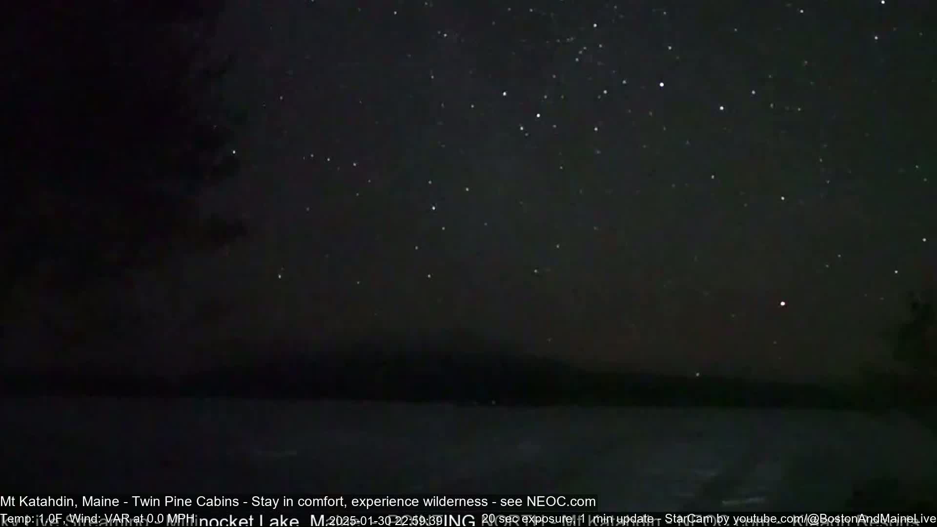 A nighttime long exposure shot shows a dark body of water under a clear, star-filled sky.
