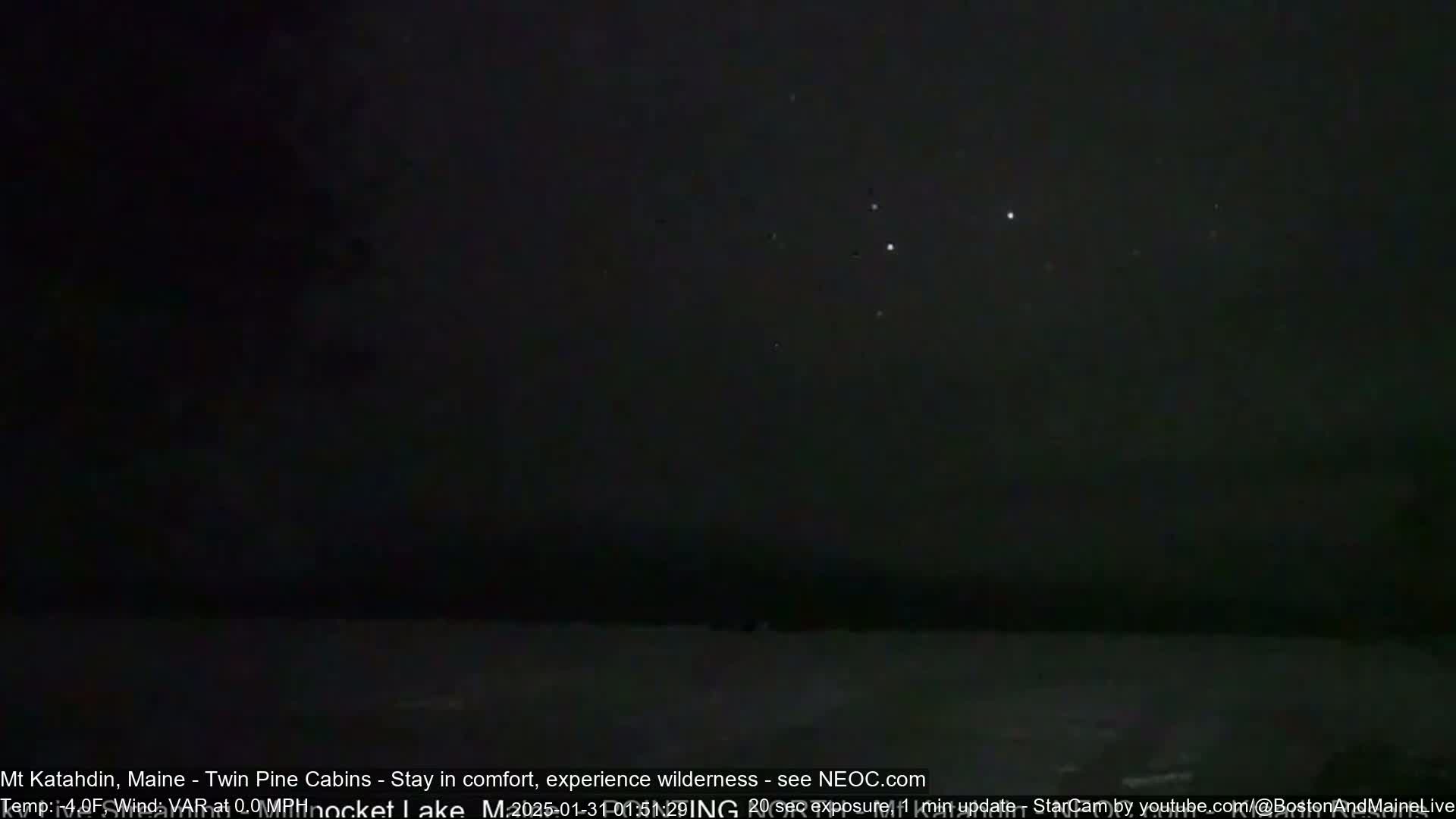 A dark, nighttime scene shows a few bright stars in the sky above a dark body of water.