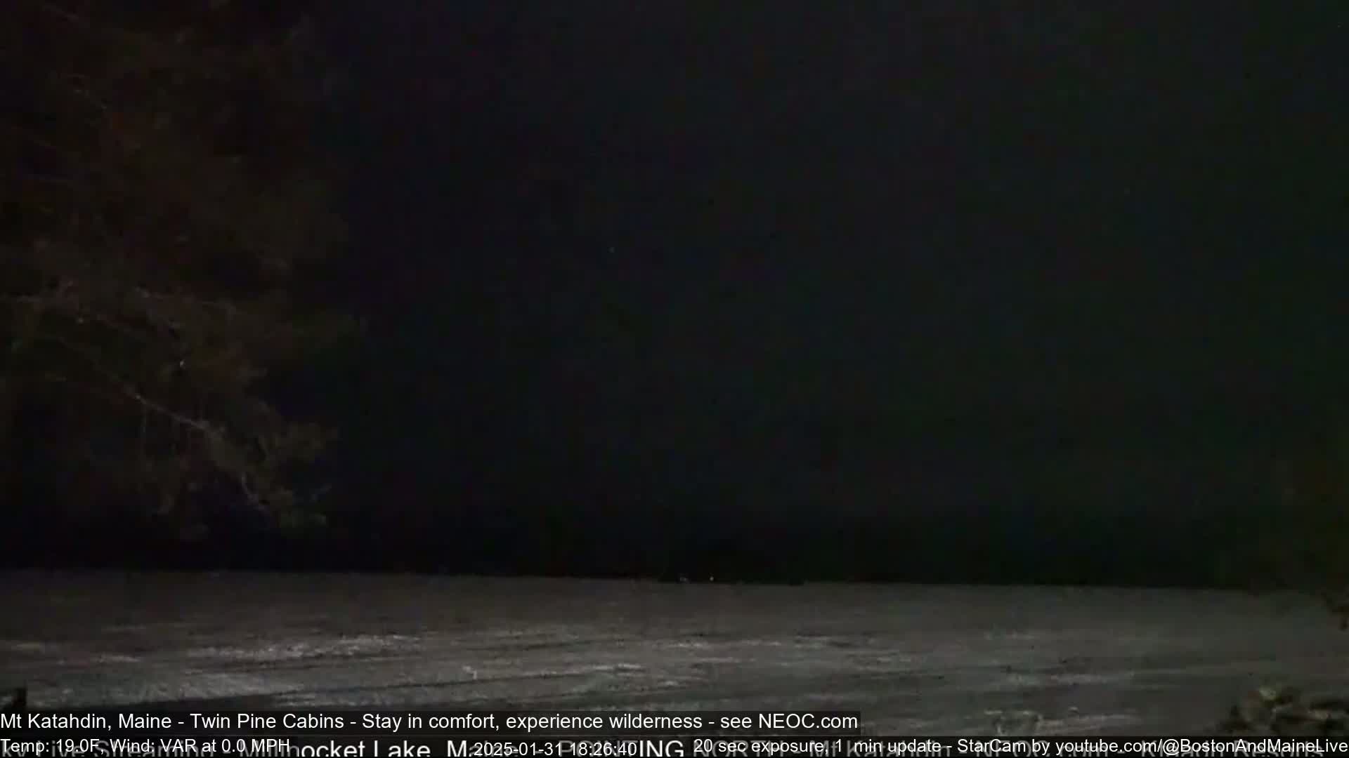A dark, nighttime scene shows a body of water mostly frozen over under a nearly black sky.