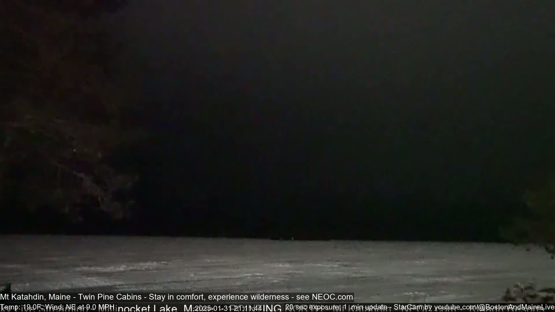 A dark, nighttime scene shows a body of frozen water under a very dark sky with a northeast wind.