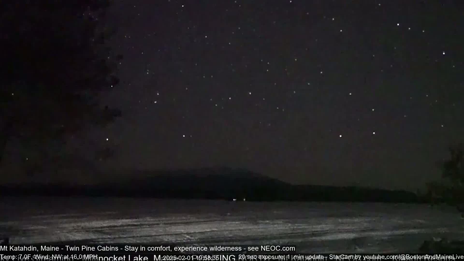 A dark, snowy landscape is visible under a clear night sky full of stars.