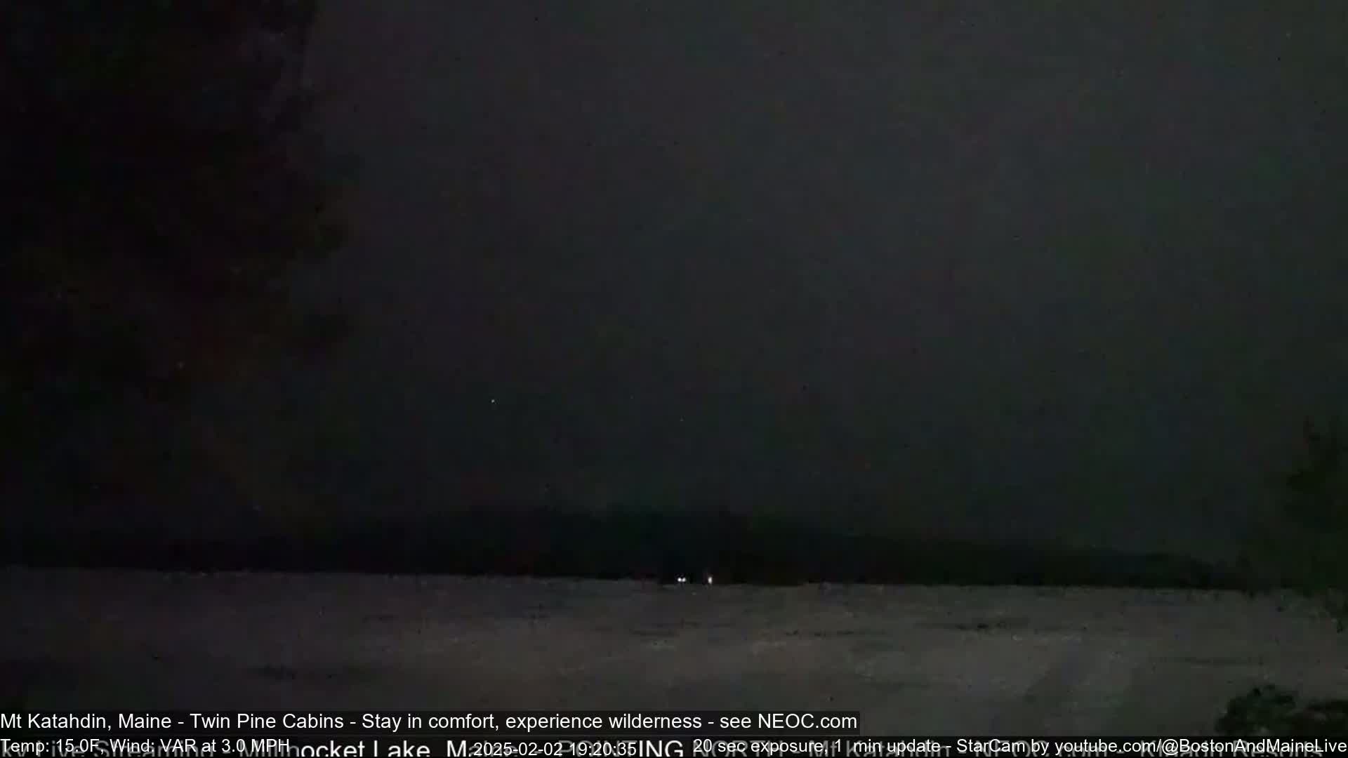 A dark, snowy landscape is visible under a nearly black night sky.