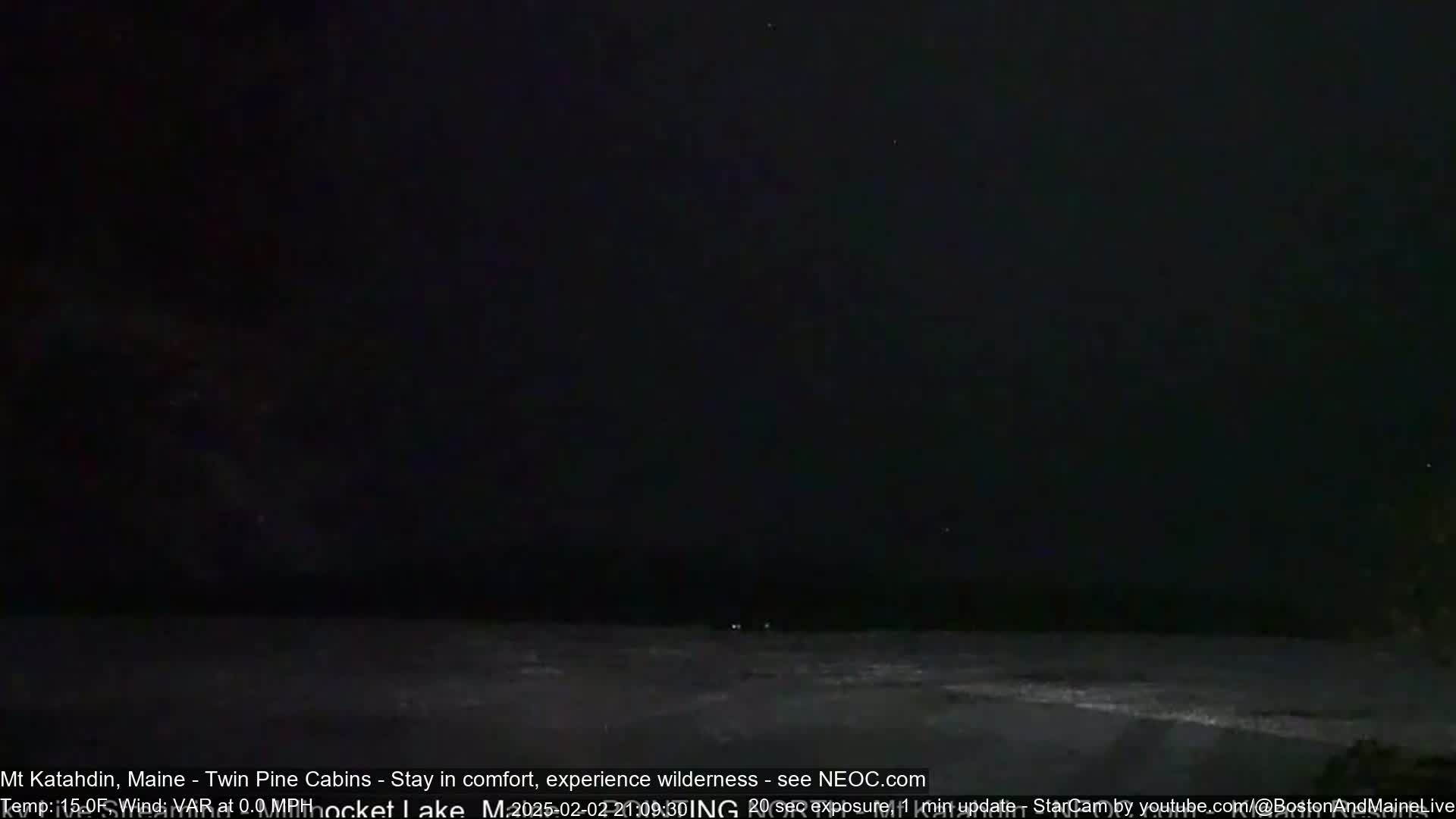 A dark, nighttime scene shows a body of water under a completely black sky.
