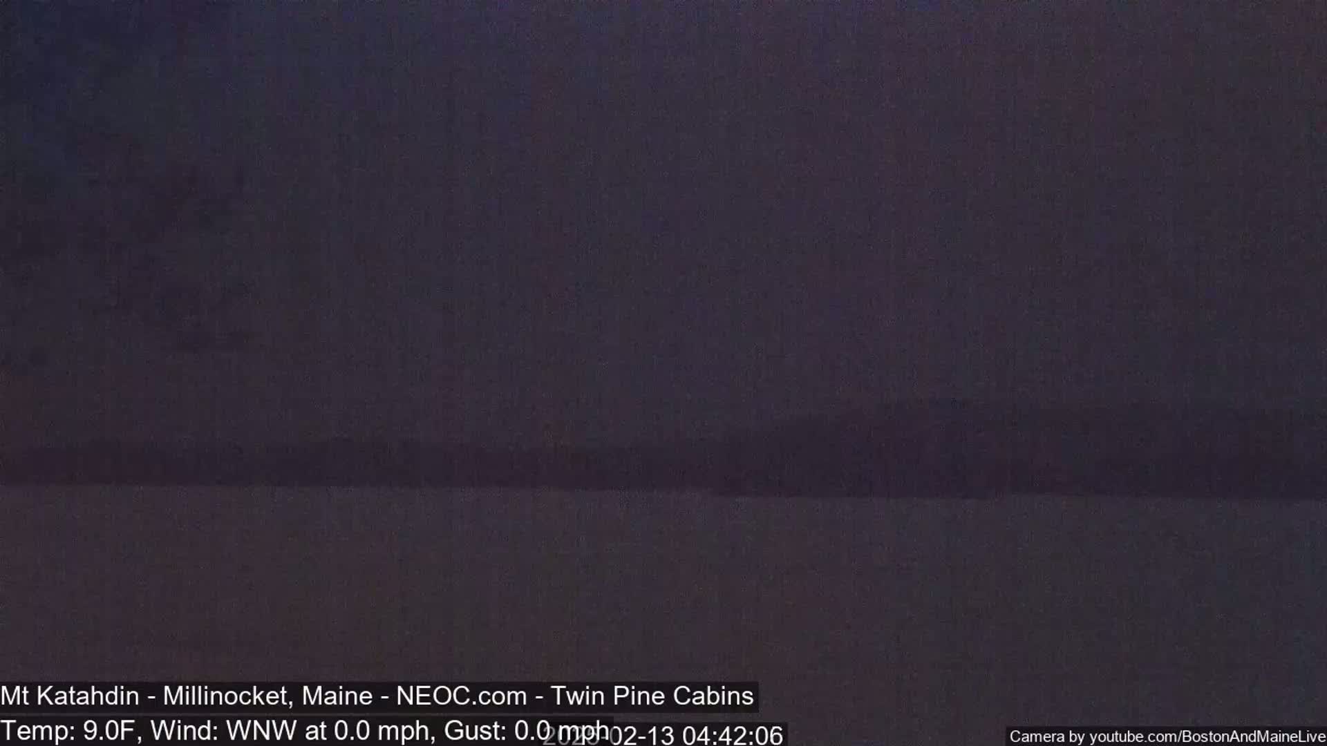 A dark, nighttime image shows a dimly lit, flat landscape under a mostly clear sky.