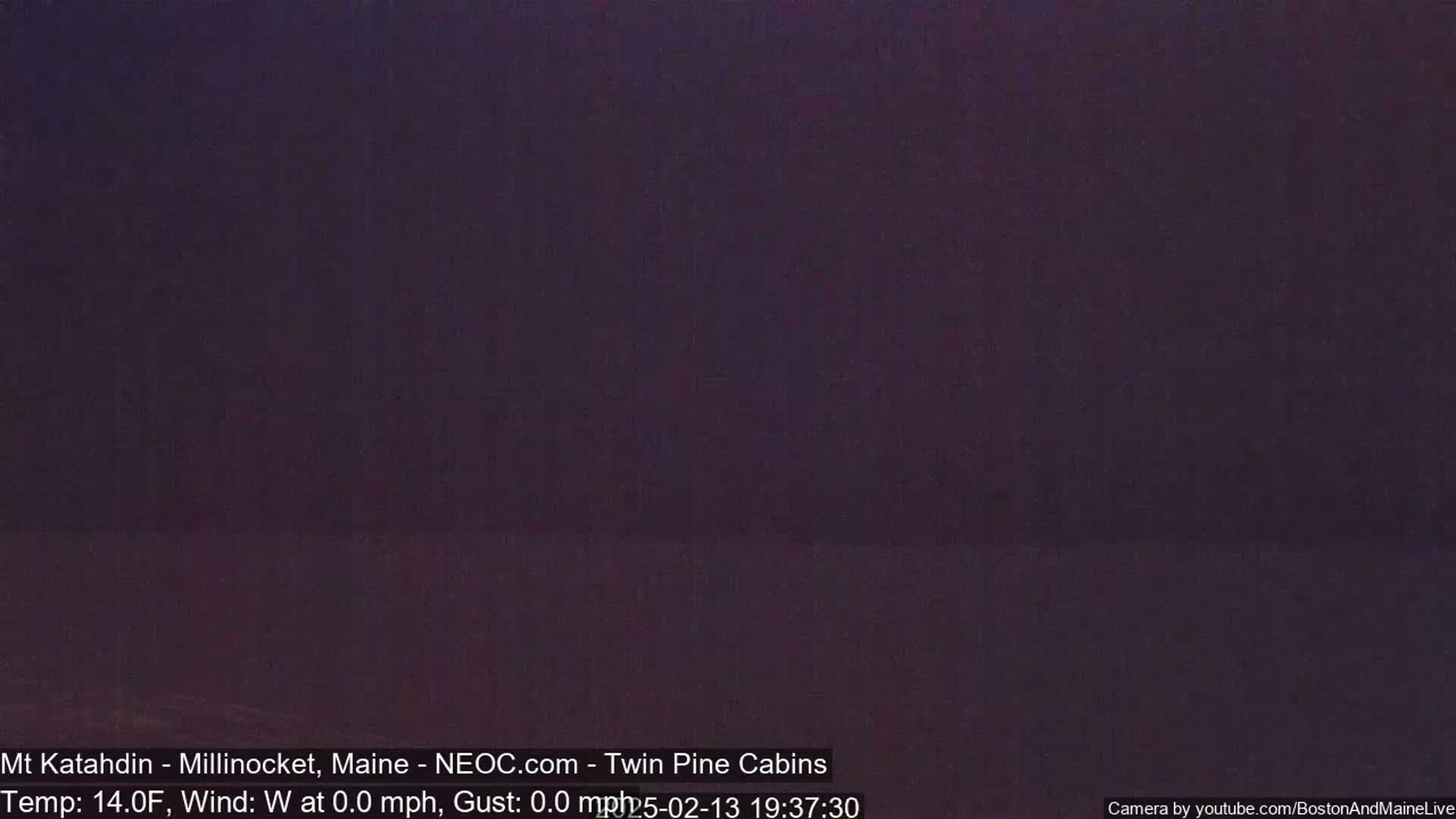 A dark, purplish-grey night scene shows a mostly featureless landscape under calm, clear skies.
