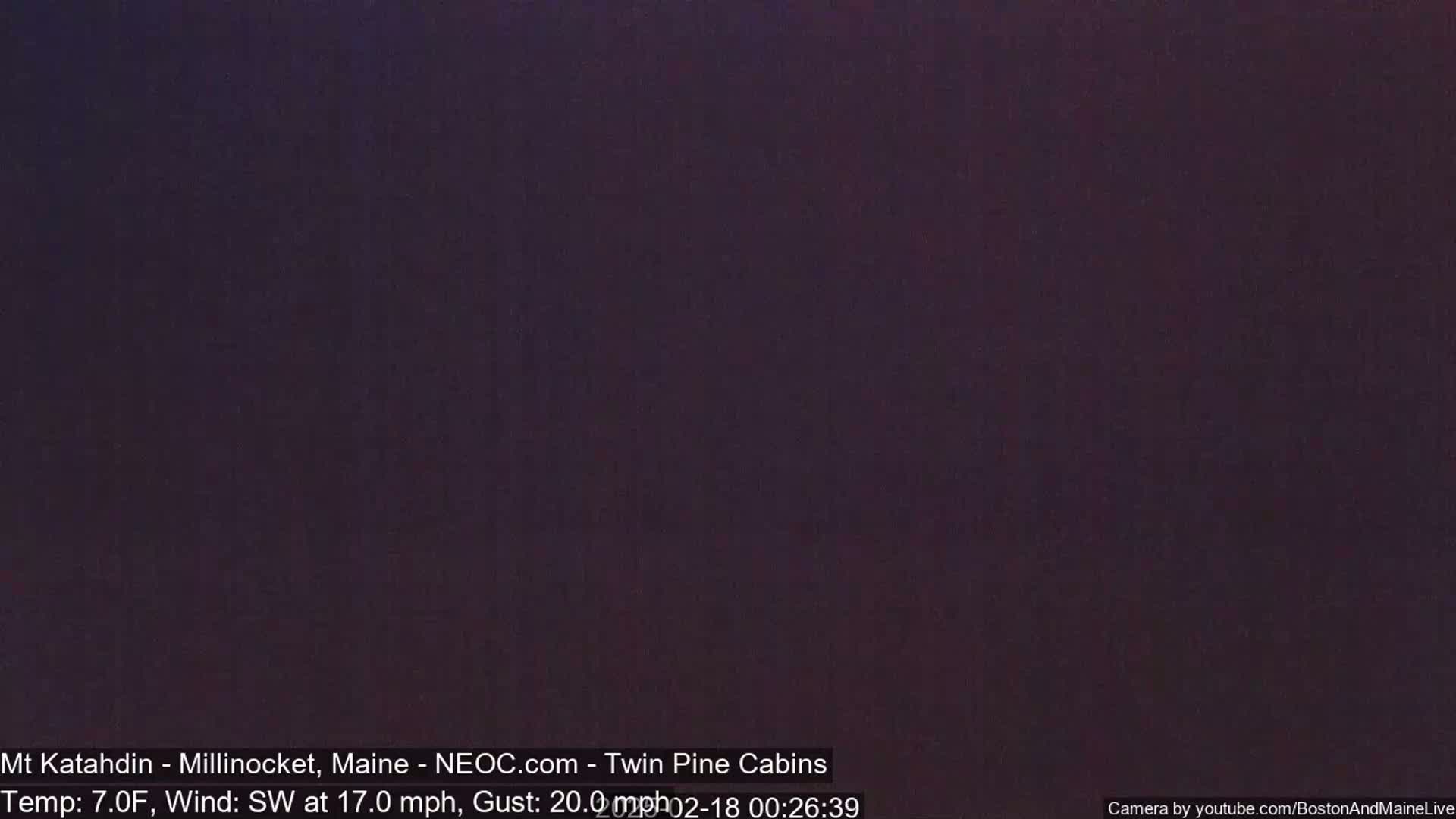 A dark, nighttime image shows a completely black scene with a dark purplish hue.
