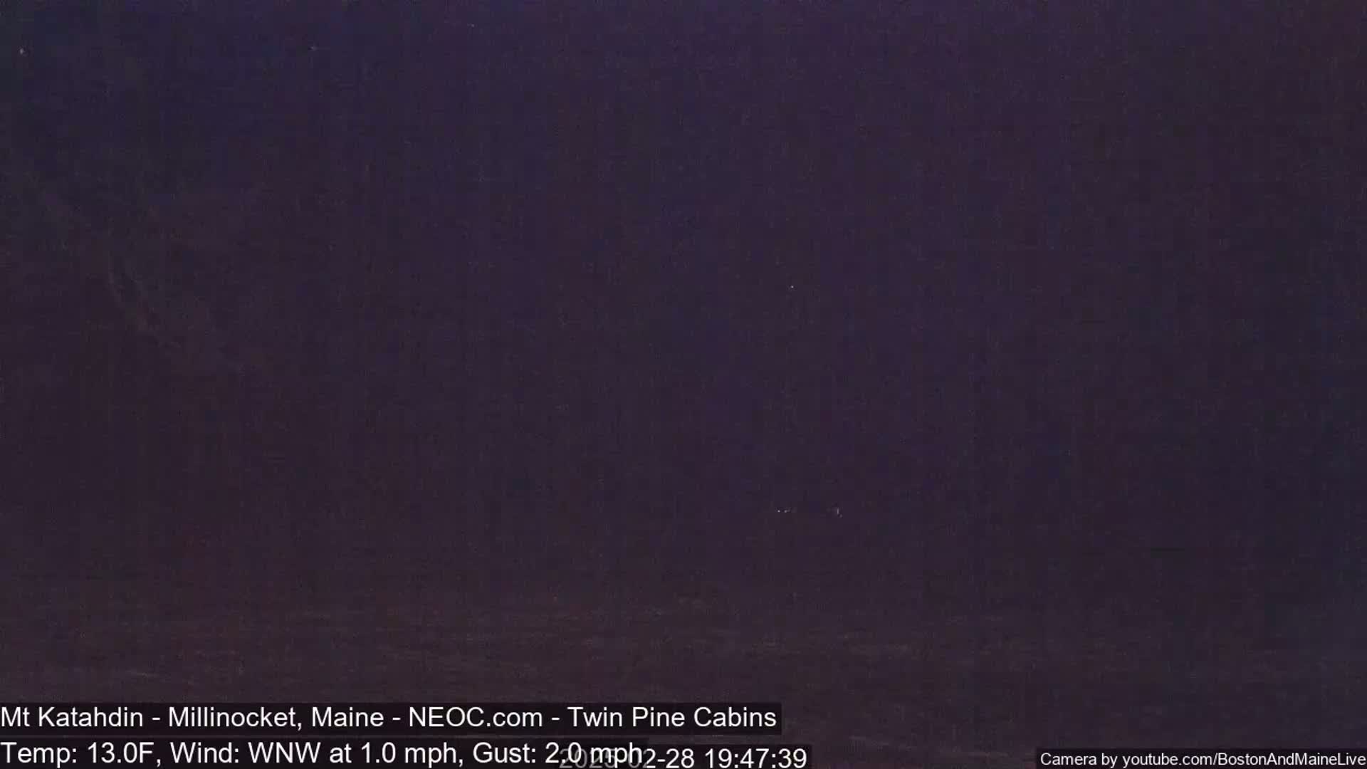 A dark, nighttime outdoor scene shows a mostly uniform dark purple hue with a hint of lighter purple near the bottom.