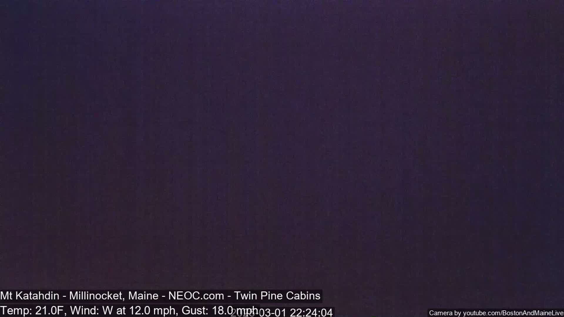 A dark purple-toned nighttime image shows a completely dark sky with a temperature of 21 degrees Fahrenheit and a westerly wind of 12 mph with gusts up to 18 mph.