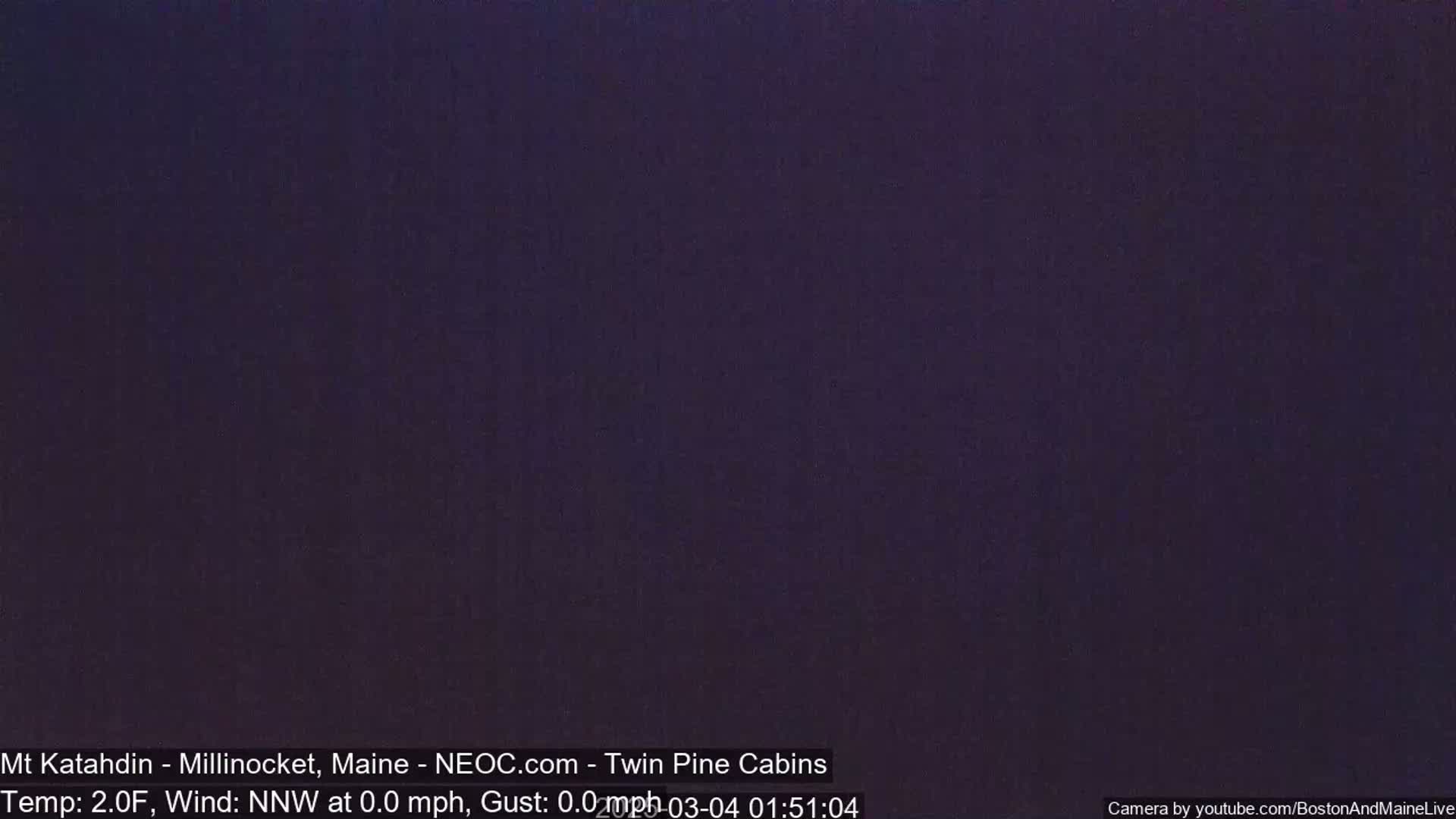 A dark purple-black image shows a nighttime, outdoor scene with a temperature of 2°F and a calm north-northwest wind.