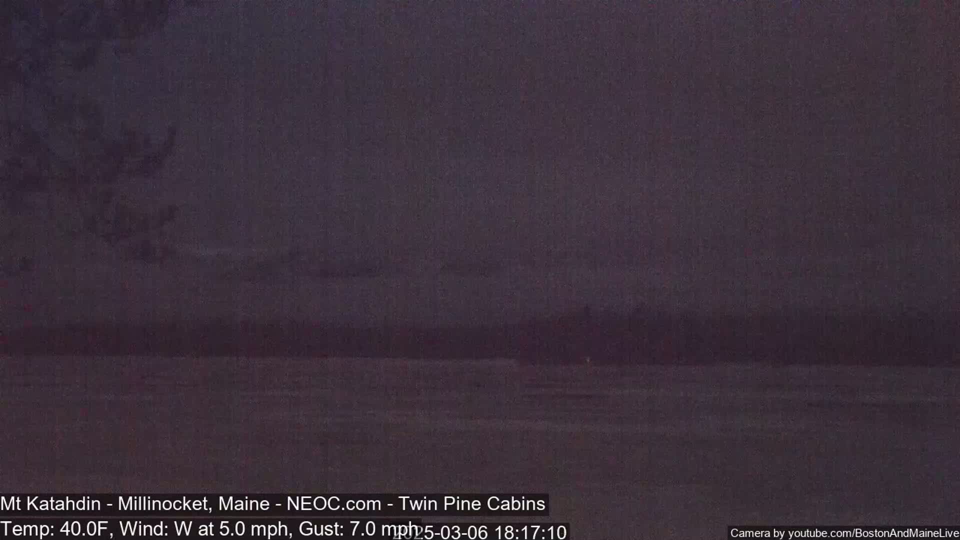 A dark, blurry view of a body of water under a dusky sky with a gentle westerly wind.