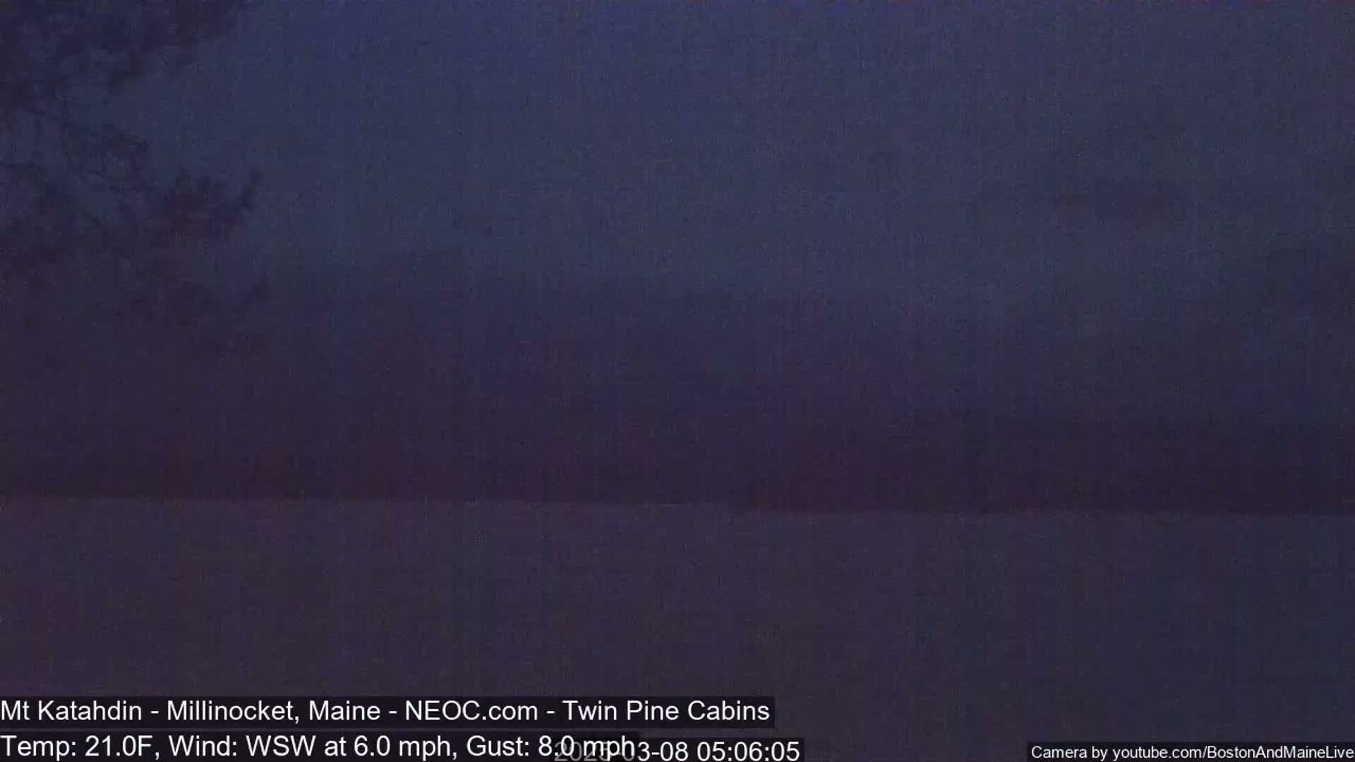 A dark, hazy view of a lake and distant mountains under a night sky.