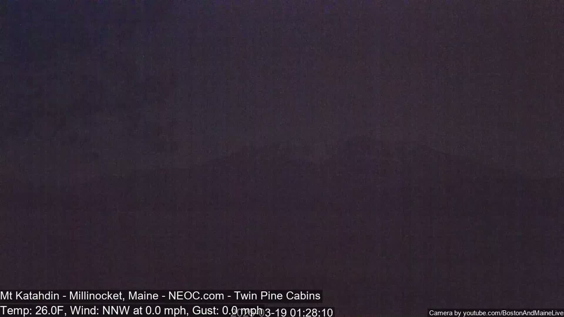 A dark, nighttime outdoor scene shows a mostly featureless, dark gray landscape under a clear sky.